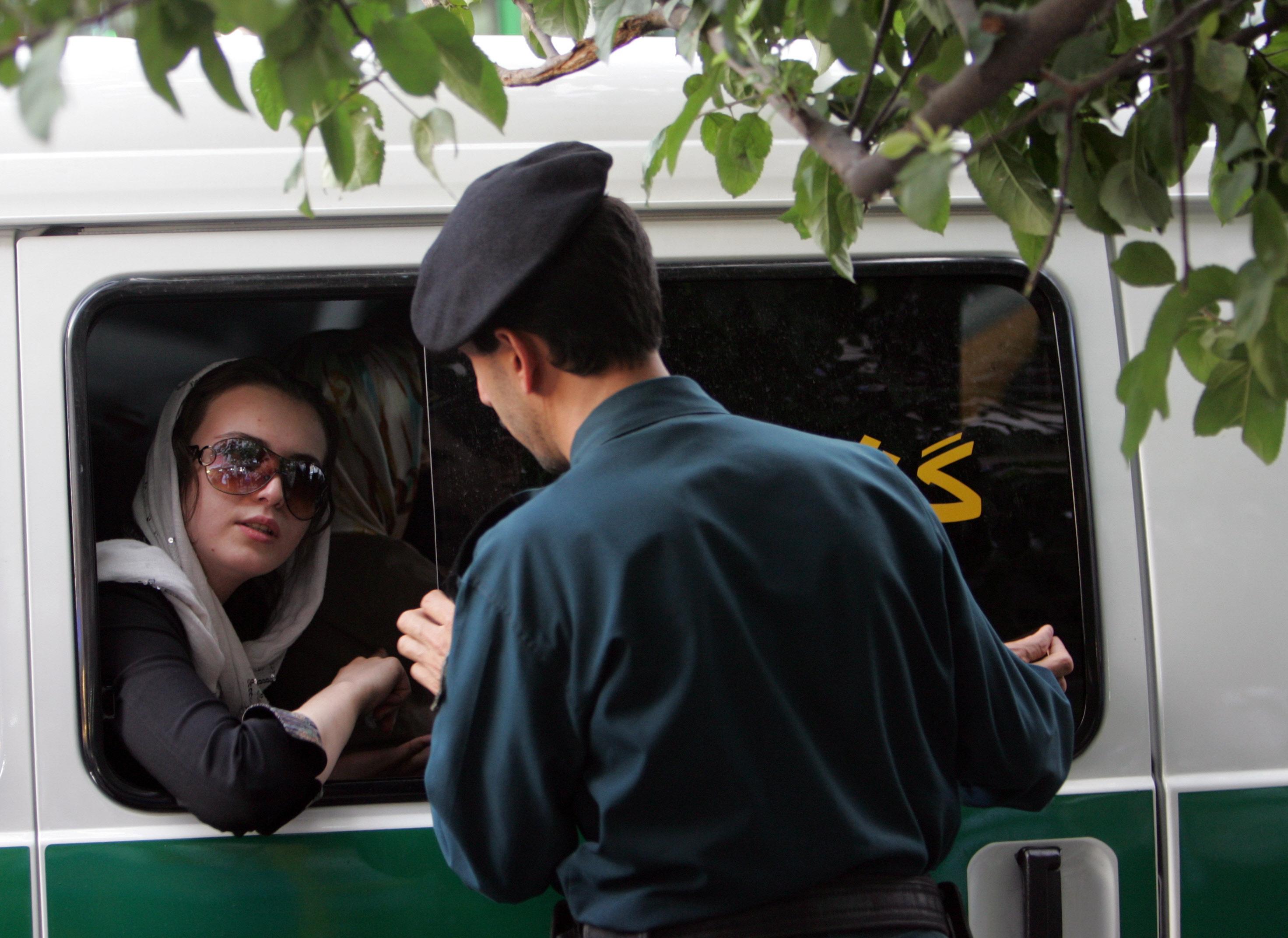 In this file photo taken on July 23, 2007, an Iranian policeman speaks with a woman siting in a police car after she was arrested because of her "inappropriate" clothes during a crackdown to enforce Islamic dress code in the capital Tehran. - Iran has scrapped its morality police after more than two months of protests triggered by the arrest of Mahsa Amini for allegedly violating the country's strict female dress code, local media said on December 4, 2022. (Photo by Behrouz MEHRI / AFP)