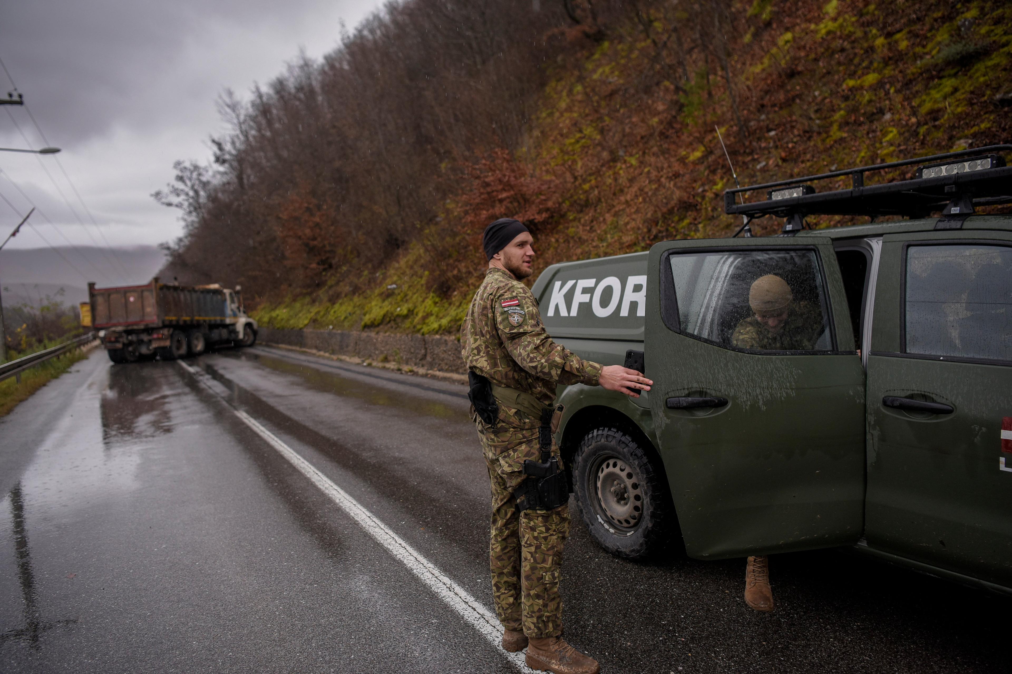 NATO soldiers serving in the peacekeeping mission in Kosovo (KFOR) inspect a road barricade set up by ethnic Serbs near the town of Zubin Potok on December 11, 2022. - Hundreds of ethnic Serbs erected barricades on a road in northern Kosovo on Saturday, blocking the traffic over the two main border crossings towards Serbia, police said. Trucks, ambulance cars and agricultural machines were used as roadblocks, heightening recent tensions which included explosions, shootings and an armed attack on a police patrol which saw one ethnic Albanian police officer wounded. (Photo by Armend NIMANI / AFP)