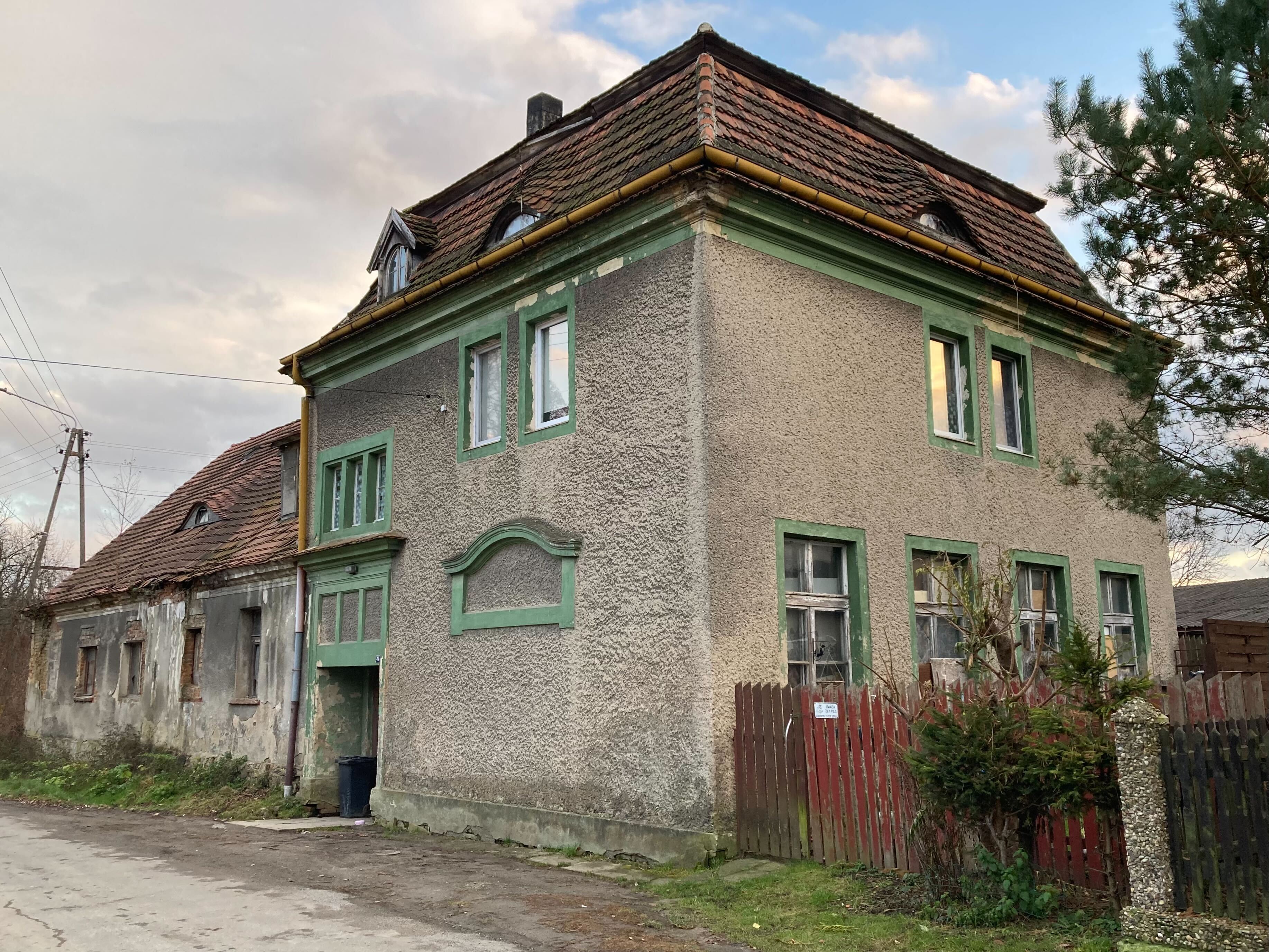 Poniemiecki dom w Sulisławicach, podniszczona elewacja, jasnozielone framugi
