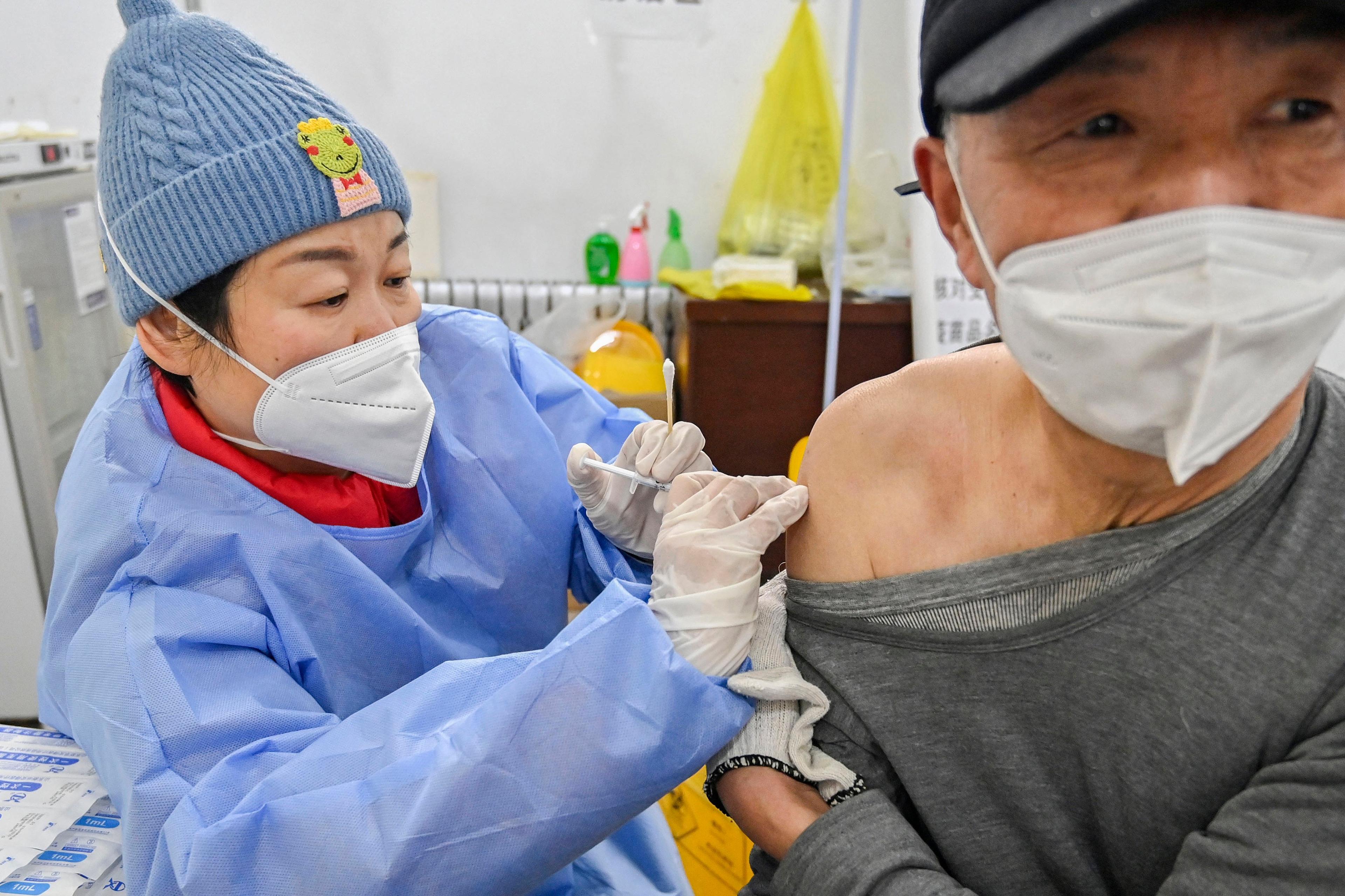 Mężczyzna, Chińczyk, w masce, dostaje zastrzyk w ramię, robiony przez pielęgniarkę