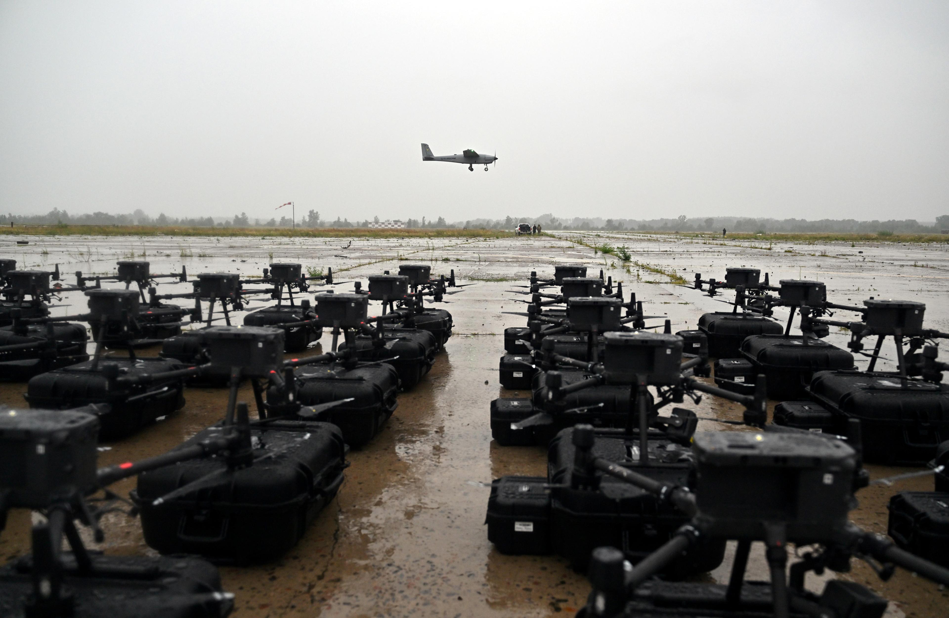 płyta lotniska, na niej w szeregach kilkadziesiąt dronów stoi na ziemi