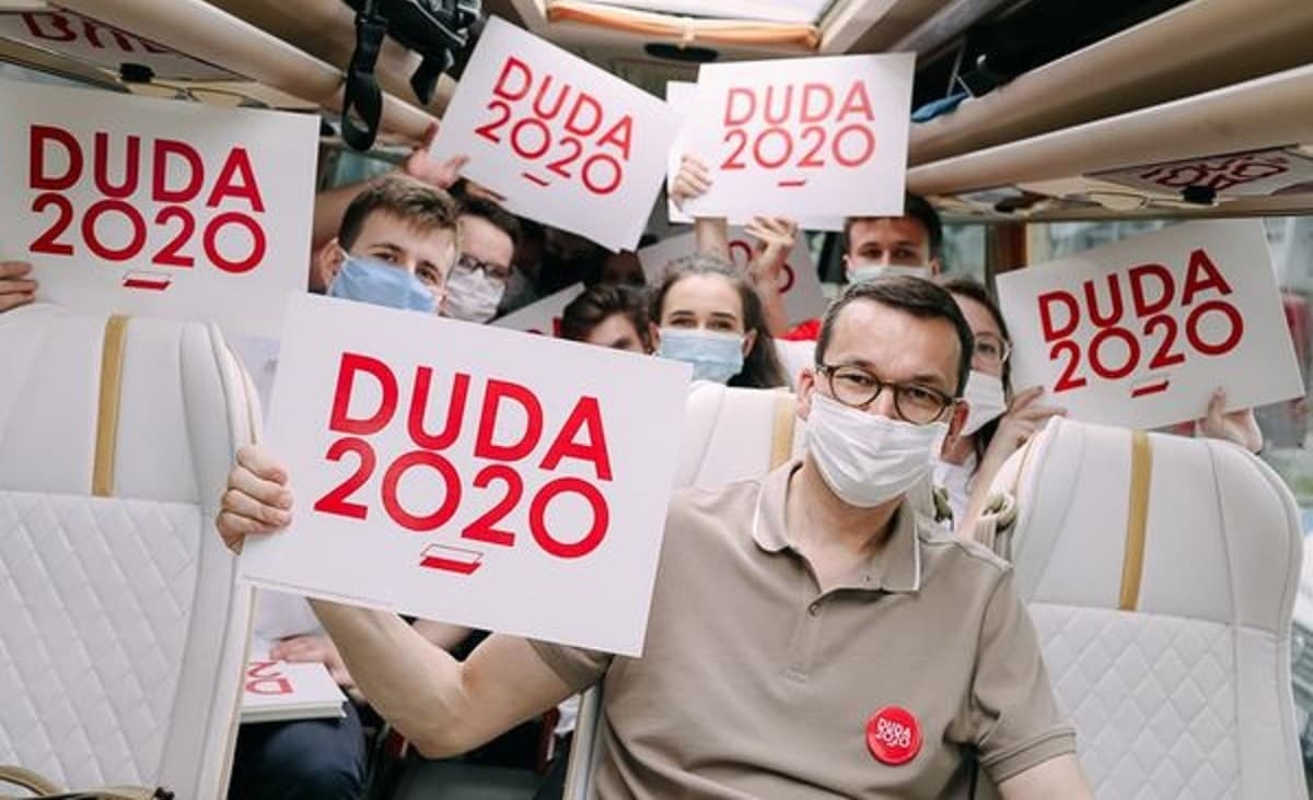 Mateusz Morawiecki w autobusie trzyma planszę z napisem Duda 2020