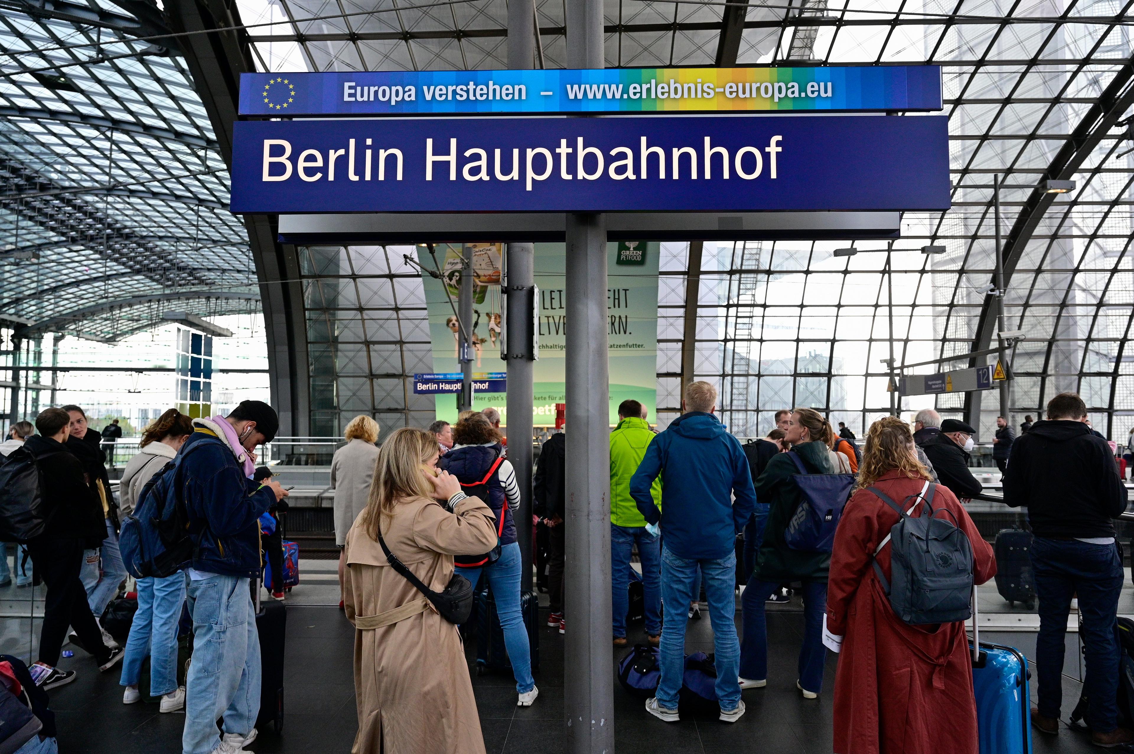 Peron kolejowy w z tlumem ludzi i niemieckim napisem "Berlin Dworzec Góówny" (Berlin Hauptbanhof)