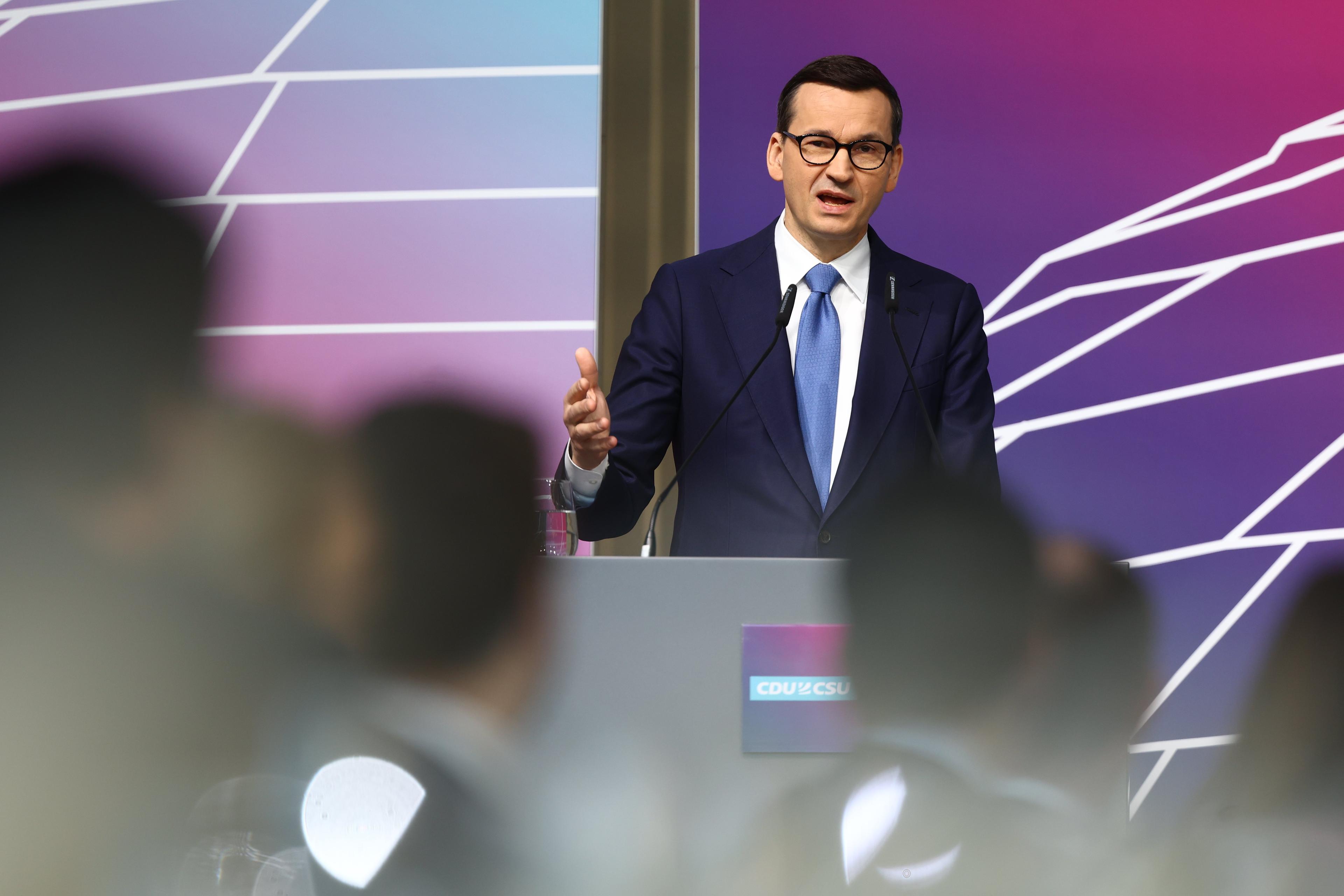 Mężczyzna w garniturze przemawia zza pulpitu. To Mateusz Morawiecki
