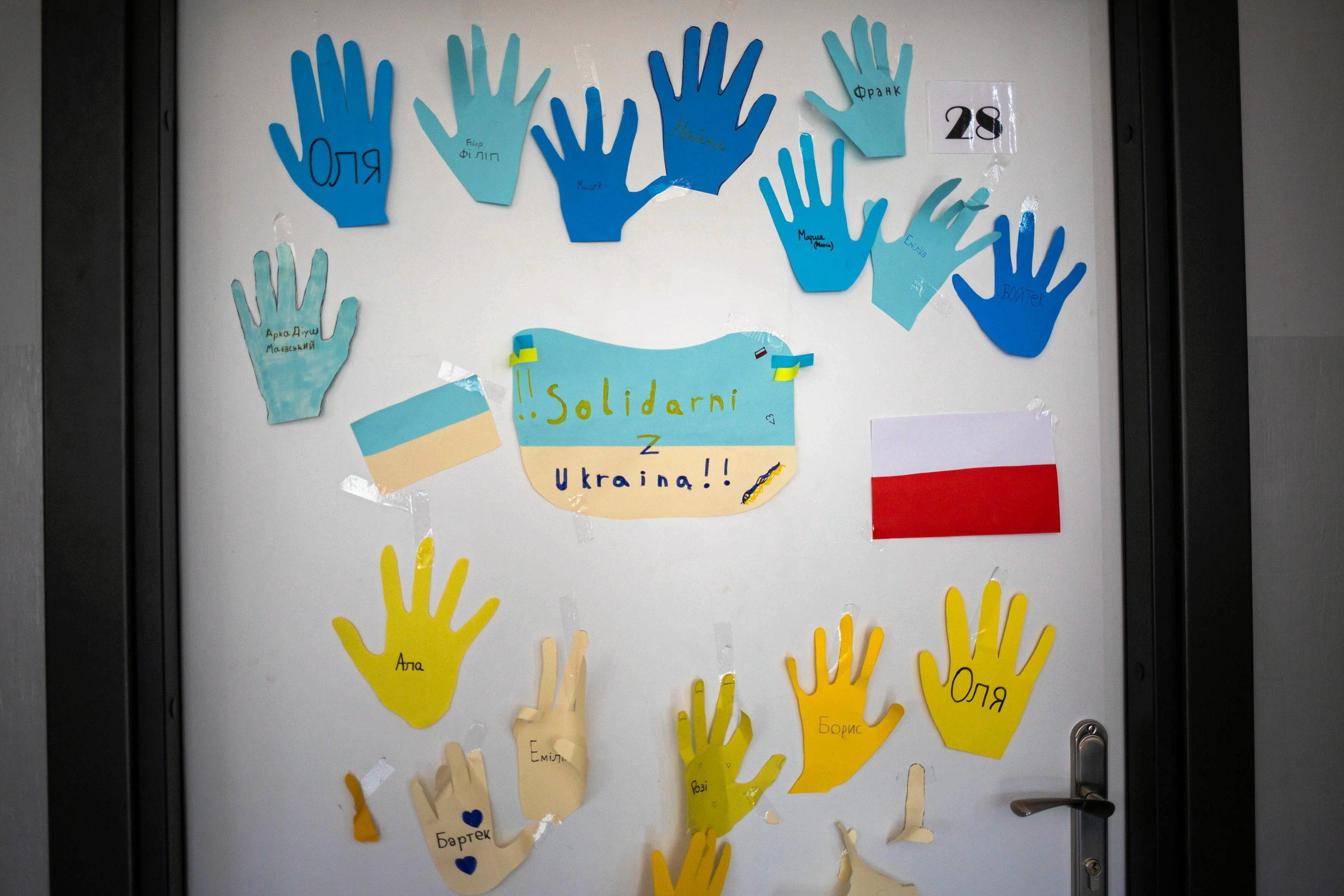 Szkolna wyklejanka: niebieskie i żółte dłonie, w które spiane są imiona ukraińskich dzieci. Flaga Polski i Ukrainy, napis "Solidarni z Ukrainą"