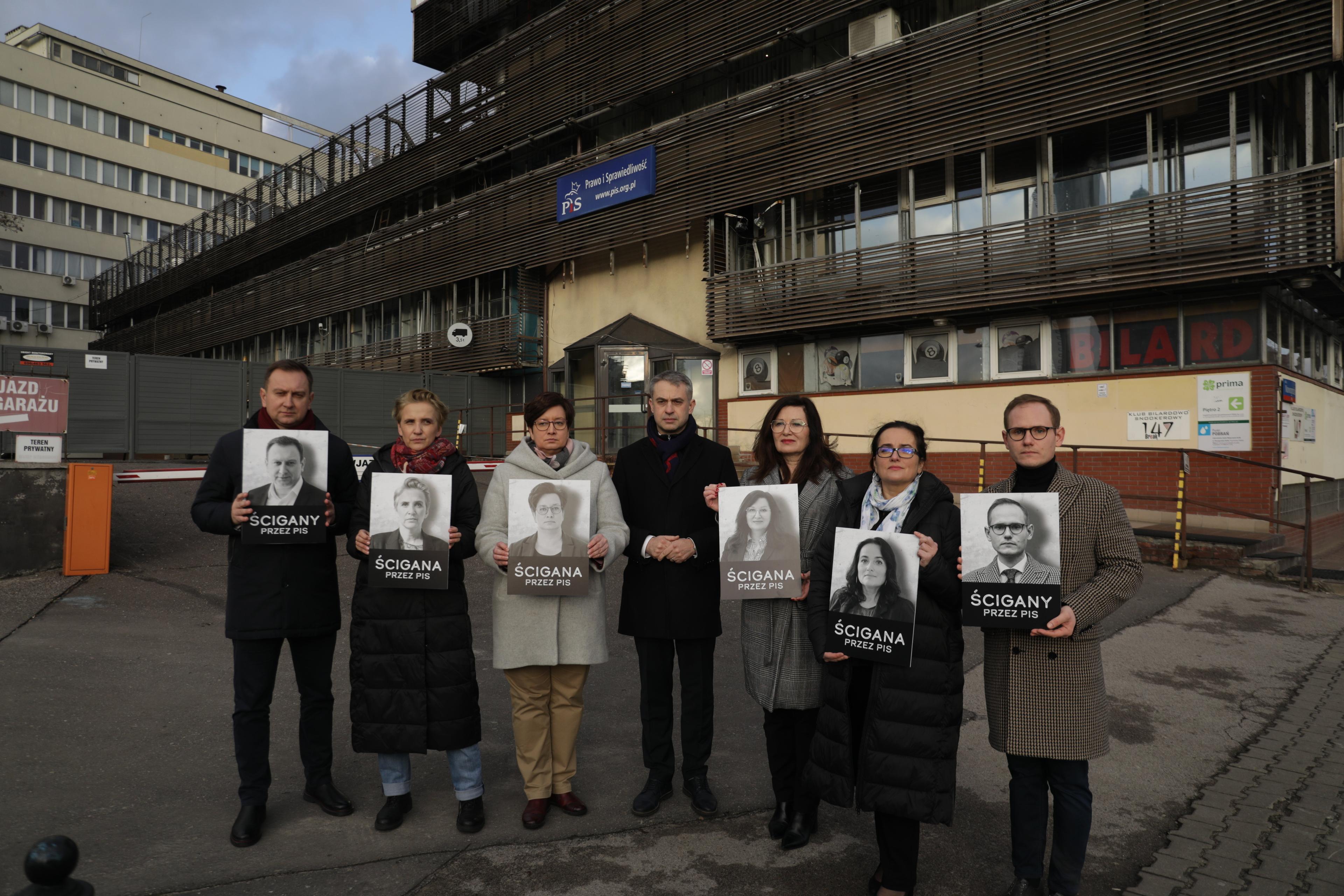 Sześć osób pozuje do zdjęcia trzymając swoje fotografie z napisem "Ścigany/Ścigana"