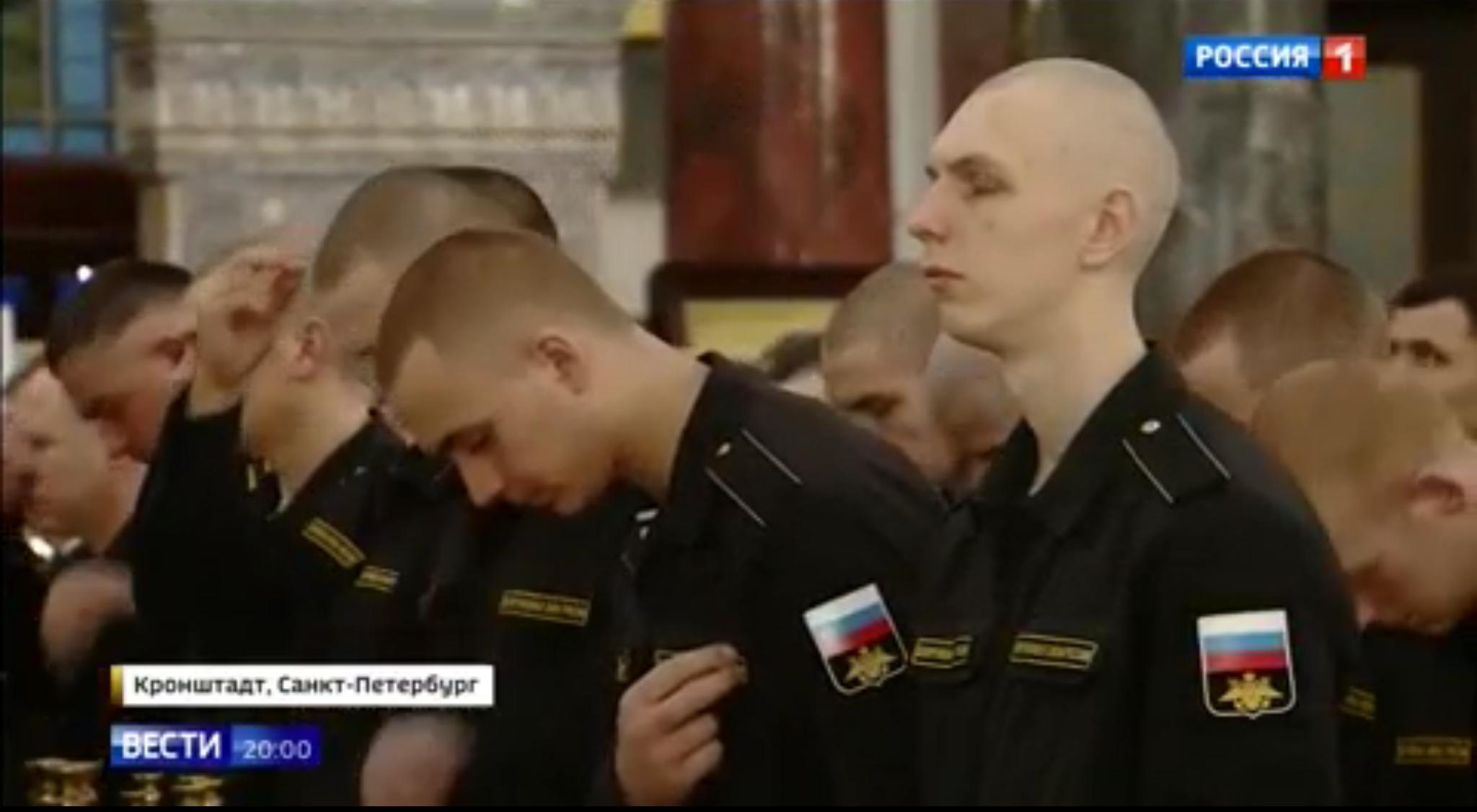 Młodzi żołnierze krótko ostrzyżeni żegnają się i kłaniają ikonom w cerkwi