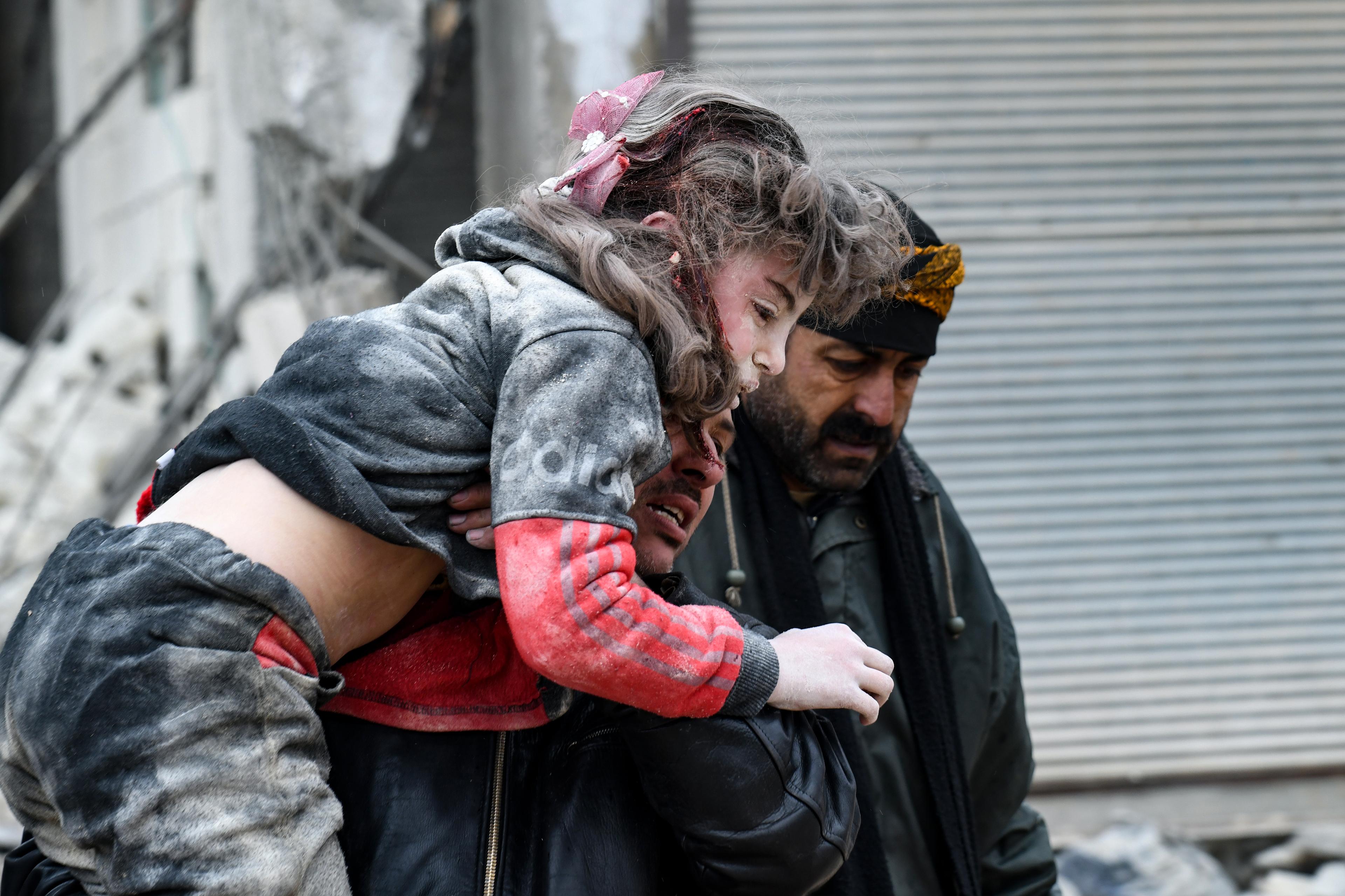 Dziewczynka, ofiara trzęsienia ziemi w Turcji i Syrii wynoszona przez mężczyznę z ruin zawalonego budynku.