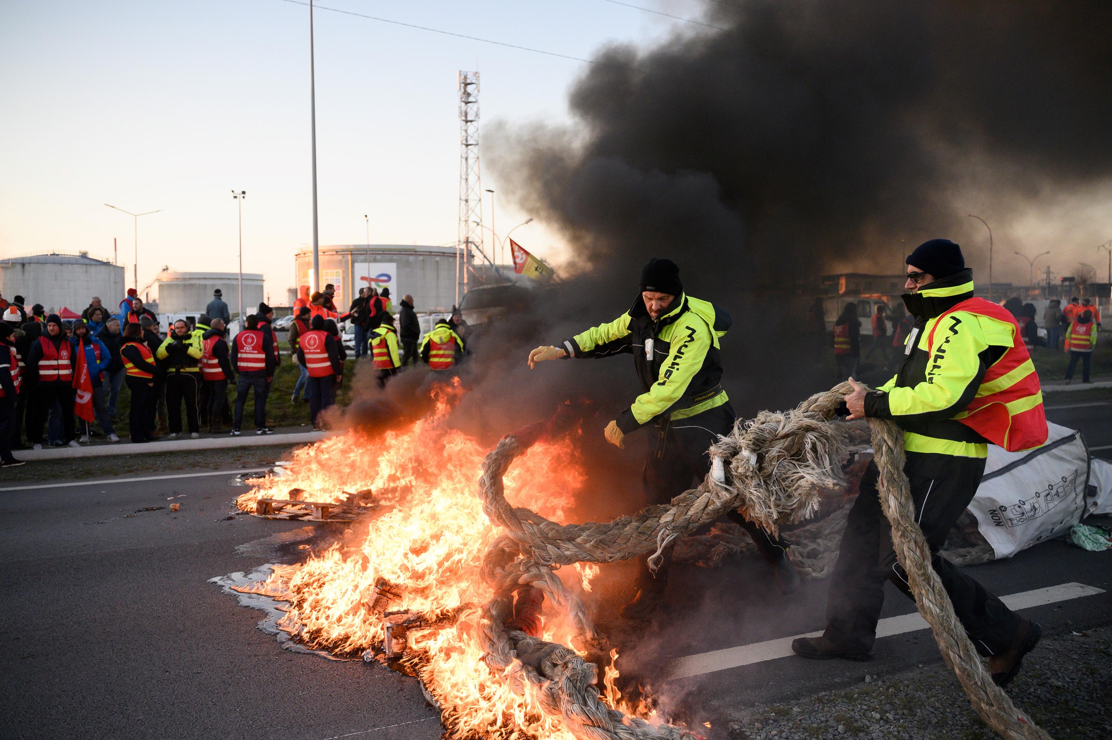 Dozens of unionists set a fire to block a road in front of the Total Energies refinery during an action called by the French union General Confederation of Labour (CGT) against a deeply unpopular pensions overhaul in Donges, Western France on February 8, 2023. - France braced on February 7, 2023 for new strikes and mass demonstrations against French President's proposal to reform French pensions, including hiking the retirement age from 62 to 64 and increasing the number of years people must make contributions for a full pension. (Photo by LOIC VENANCE / AFP)