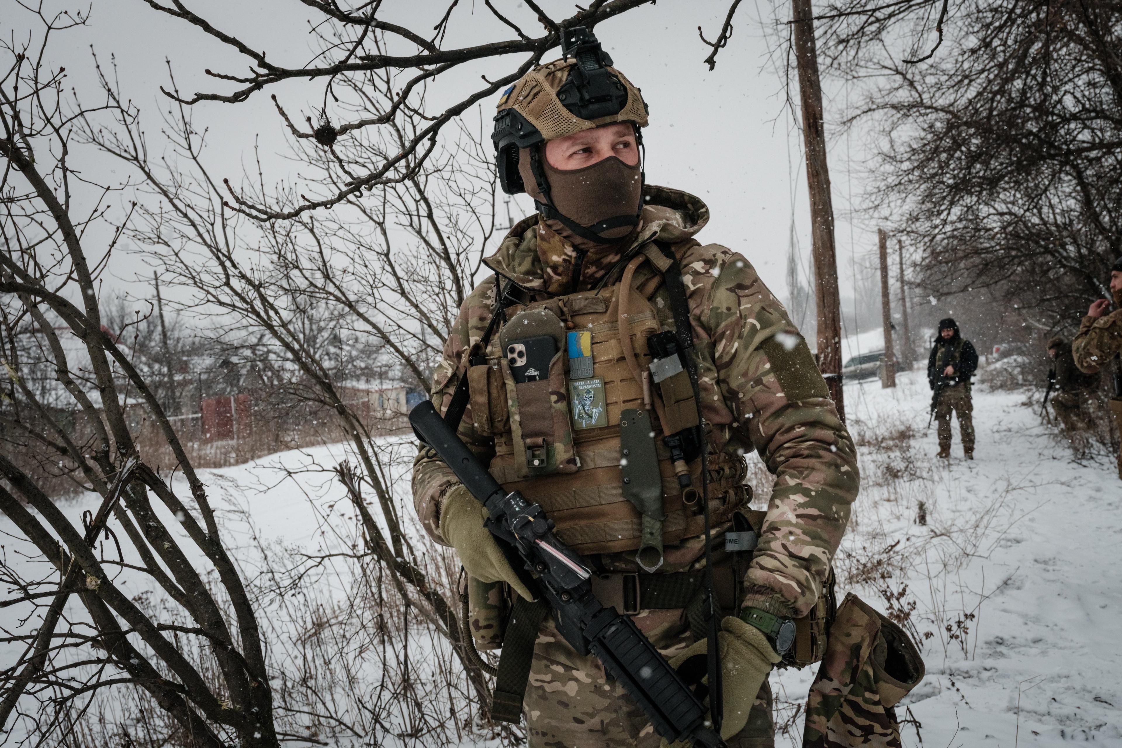 Zołnierz w bojowym rynsztunku z ukraińskimi oznaczeniami stoi na ośnieżonym polu