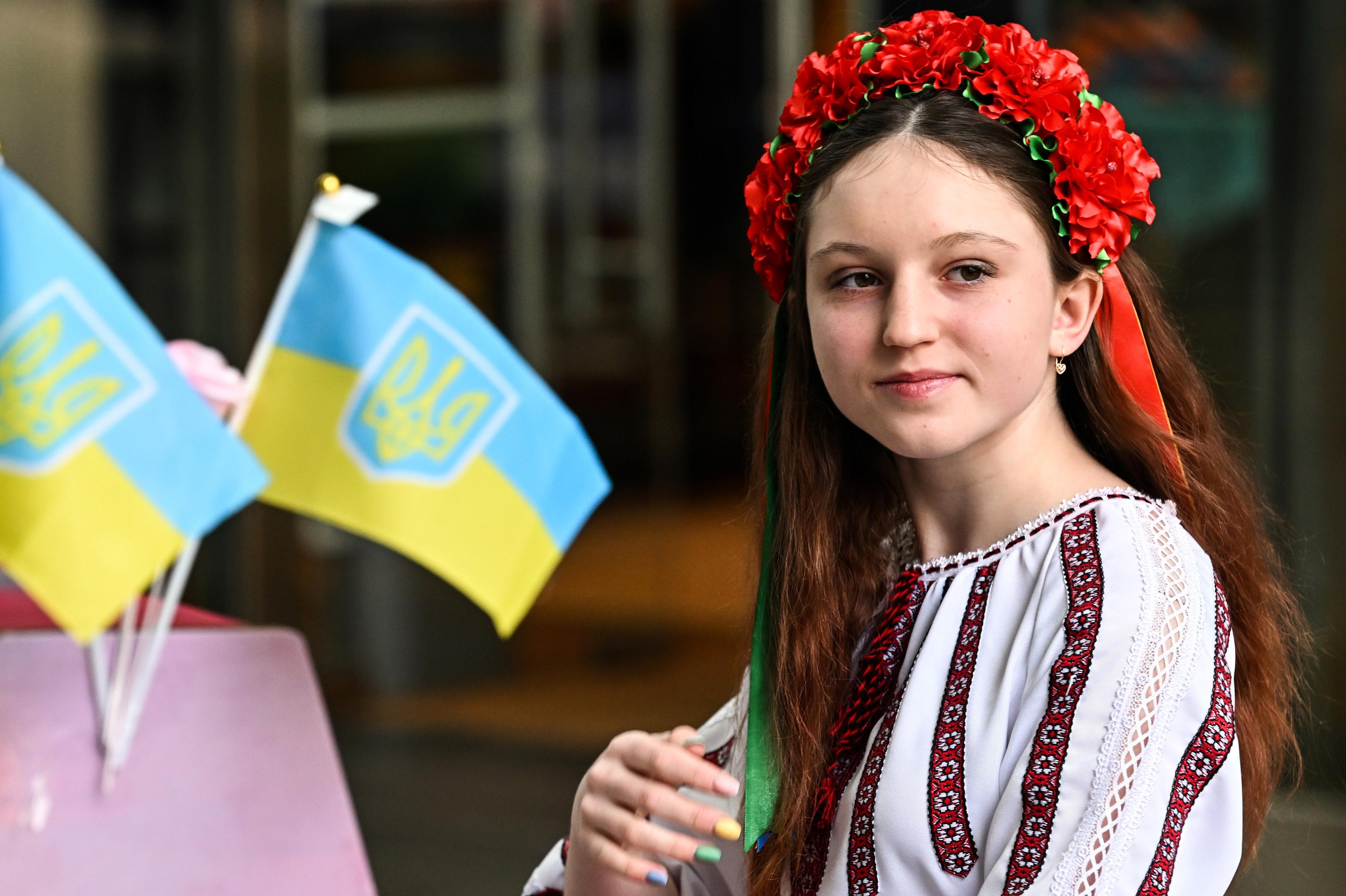 Nastolatka w ukraińskim stroju ludowym obok flag Ukrainy