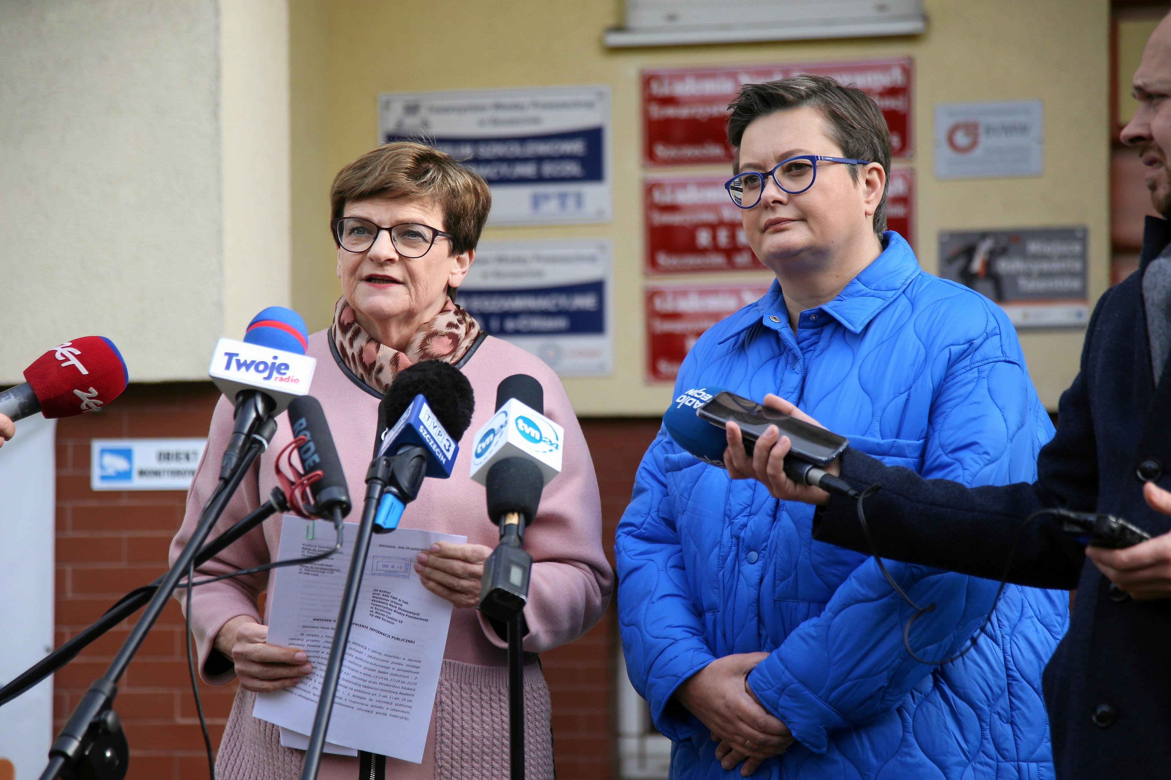Krystyna Szumilas i Katarzyna Lubnauer stoją przed mikrofonami mediów, w tle budynek z nieczytelnymi tabliczkami urzędowymi