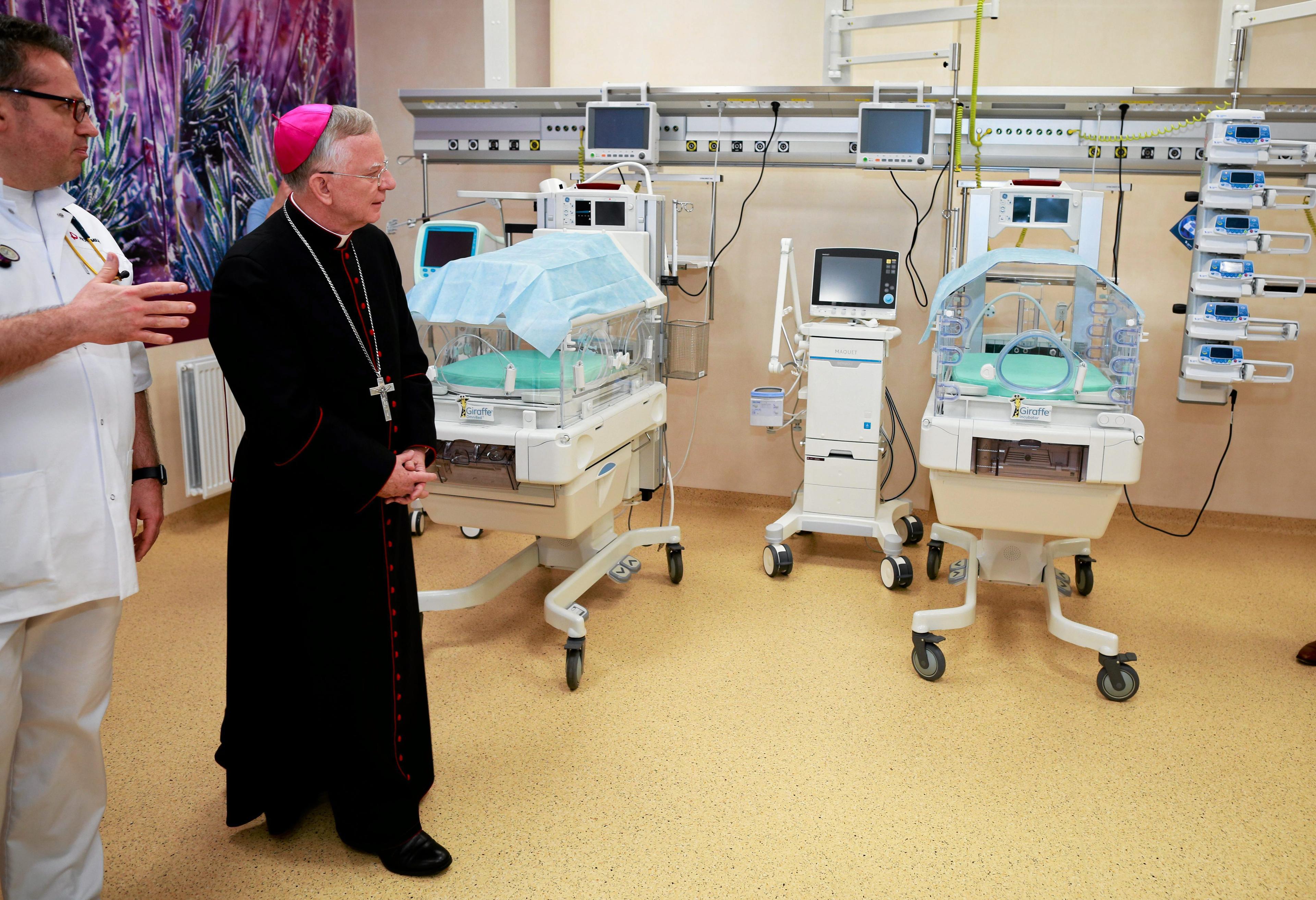 Biskup w sali szpitalnej z inkubatorami dla wcześniaków