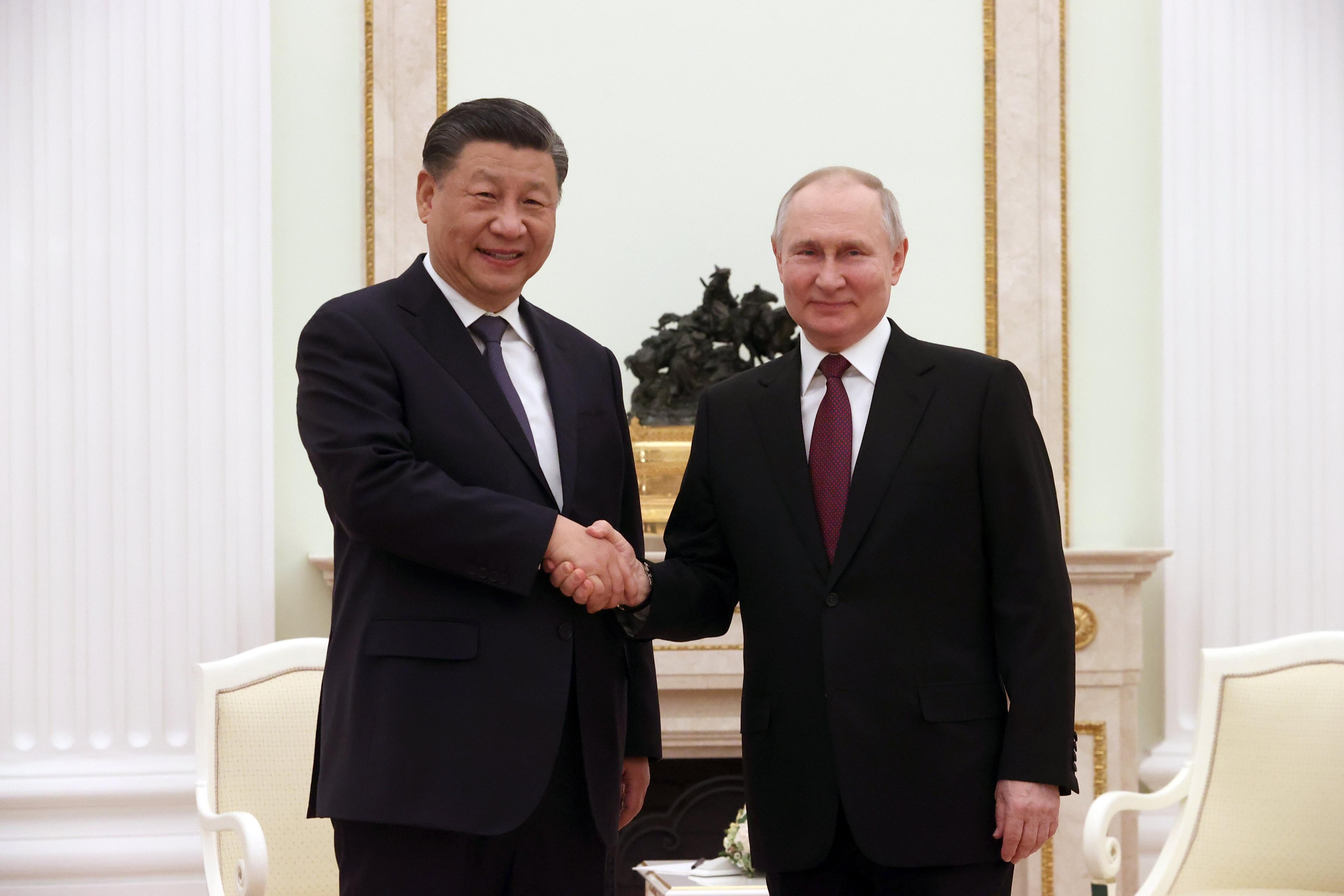 Dwaj mężczyźni w garniturach pozują ściskają dłonie. To Xi Jinping i Władimir Putin