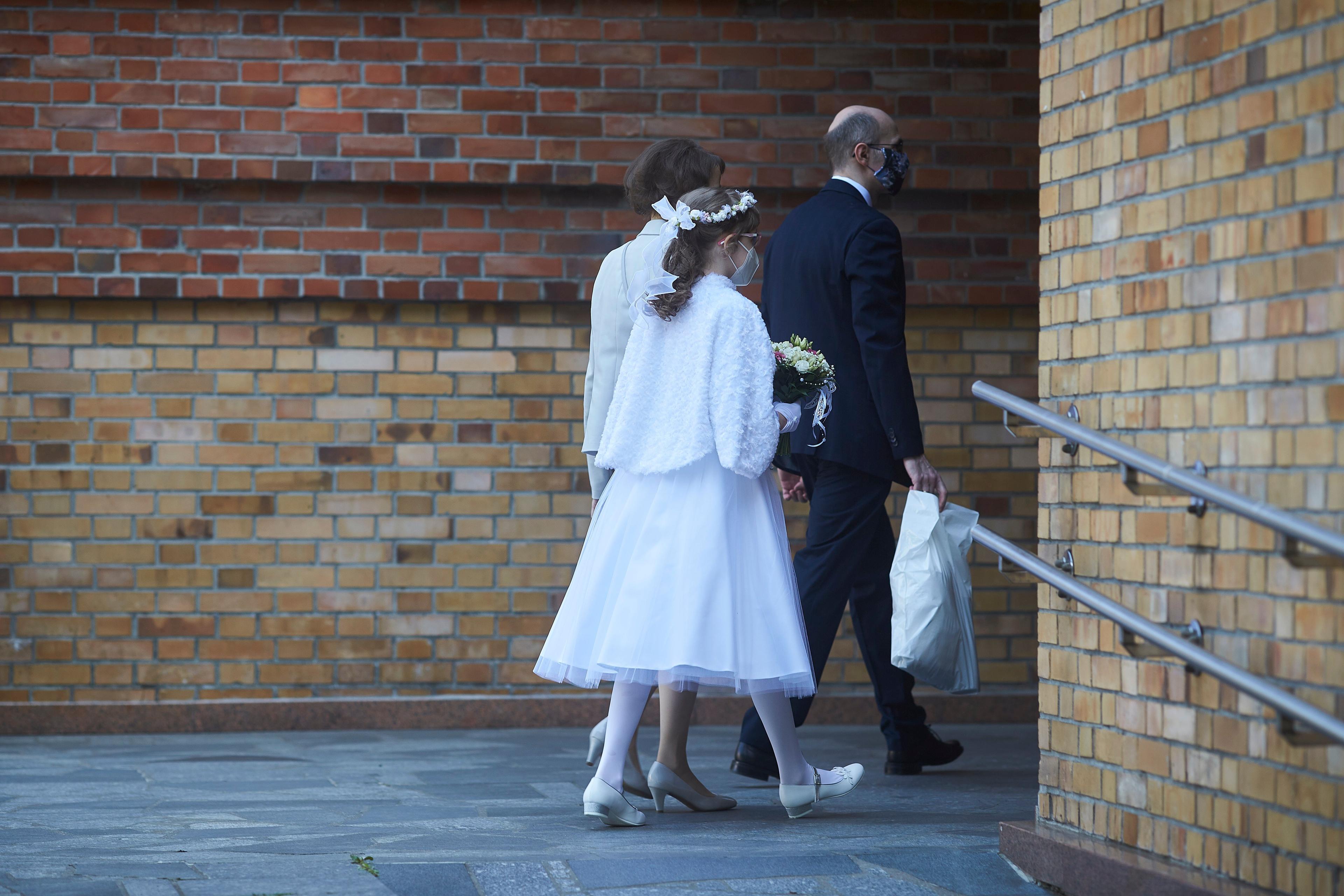 Na zdjęciu: dwie dziewczynki ubrane w białe alby i wianki wchodzą do kościoła.