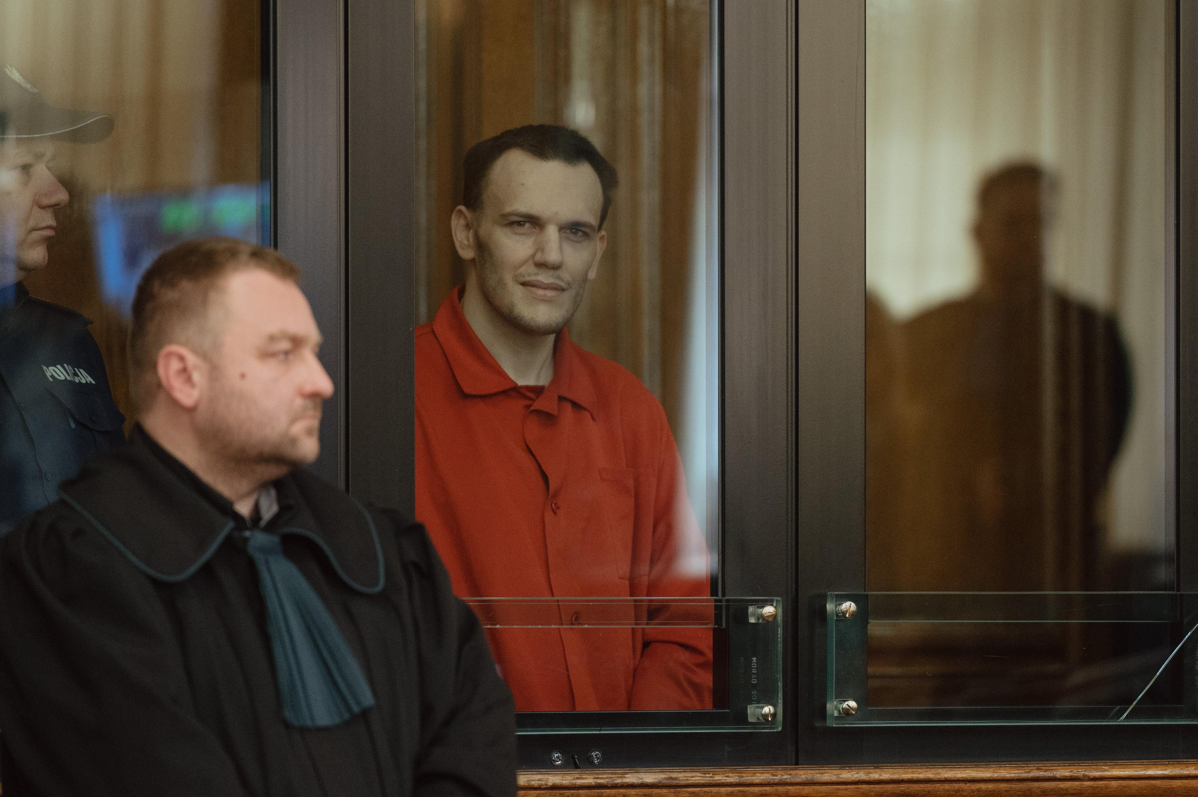 30-letni mężczyzna w czerwonych więziennych drelichach, obok adwokat w todze
