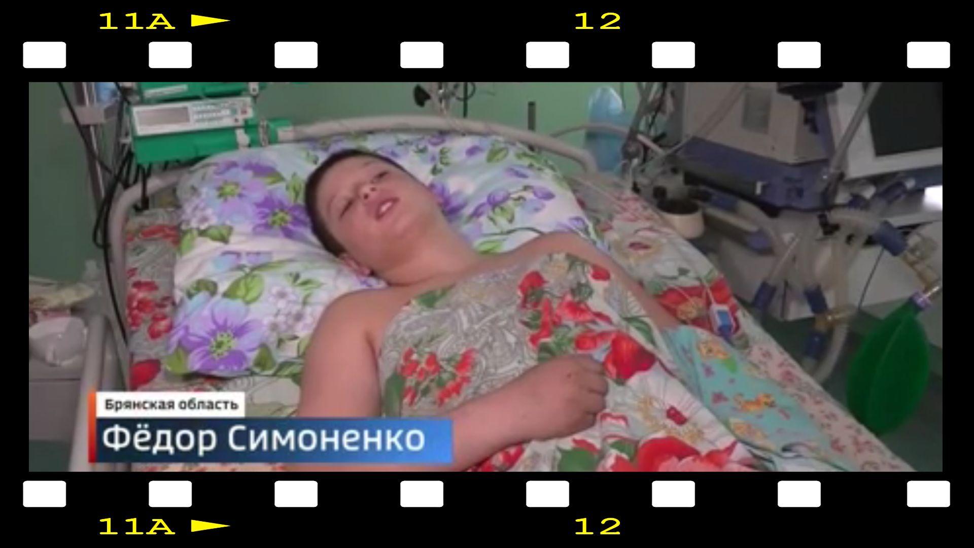 W ramkę kliszy filmowej wkleone zdjęcie chłopca w łóżku szpitalnym pod kolorową kołdrą w duże czerwone kwiaty