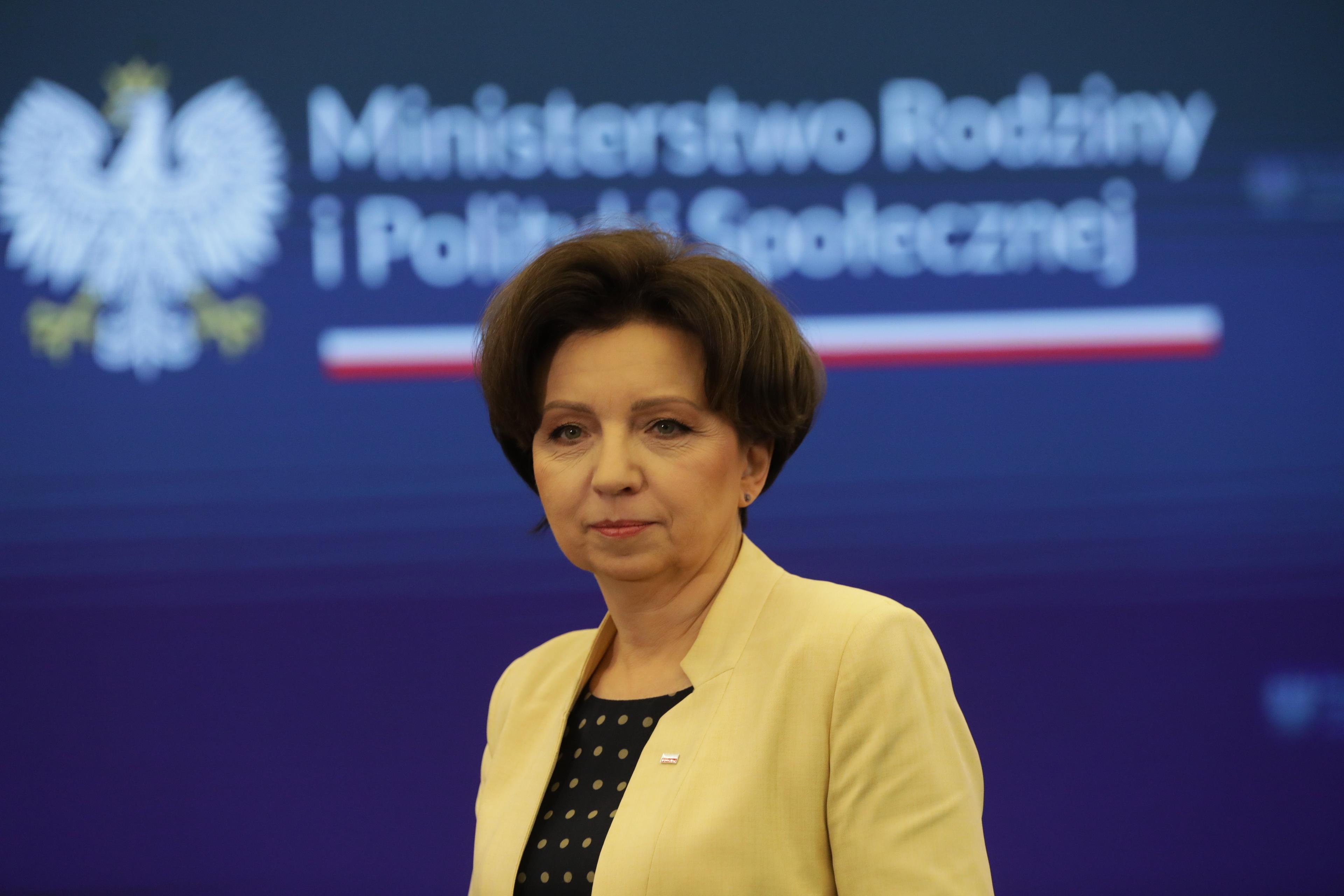 Kobieta w żółtej garsonce podczas konferencji. To minister Maląg