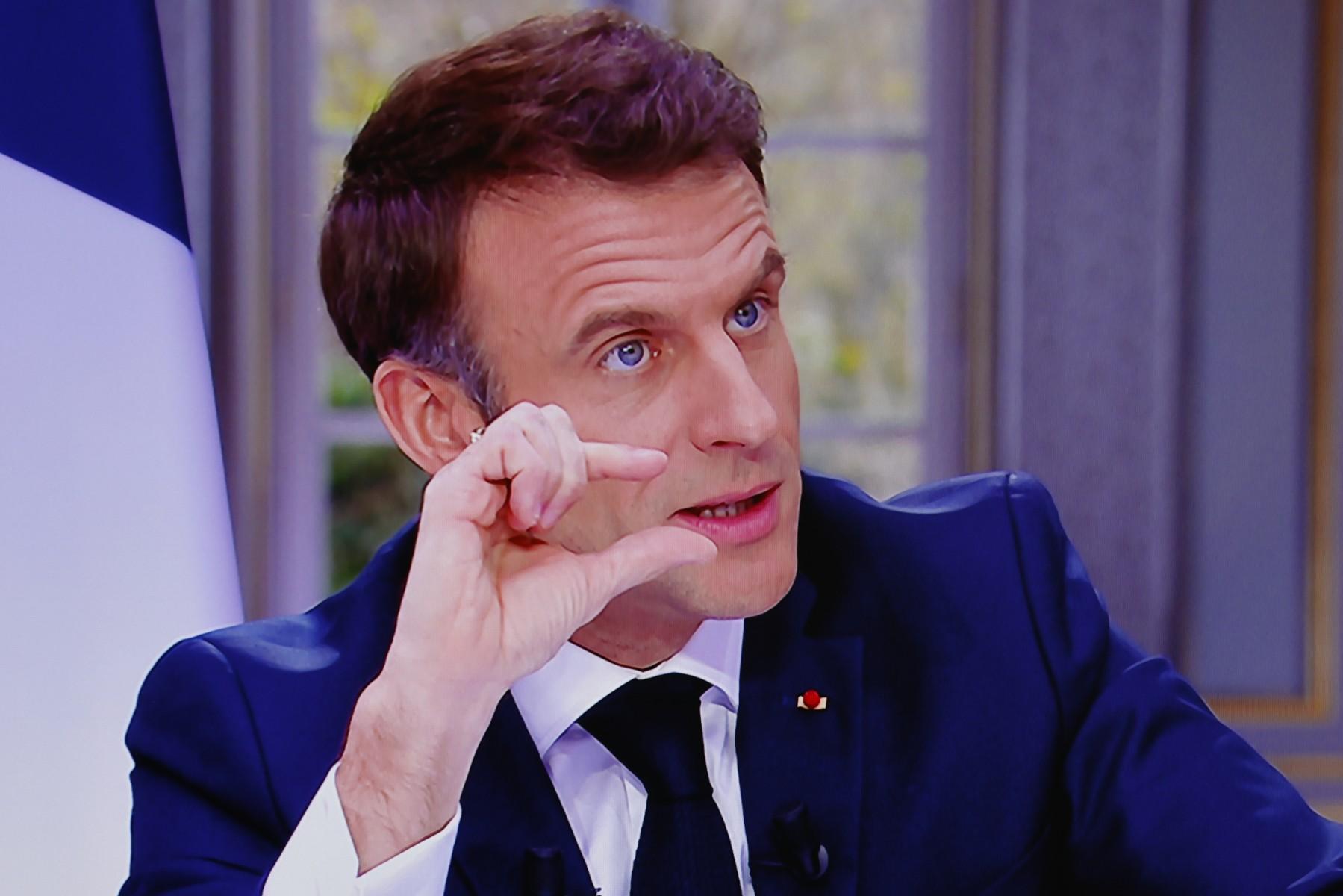 Prezydent Macron pokazuje cos dwoma palcami prawej dłoni