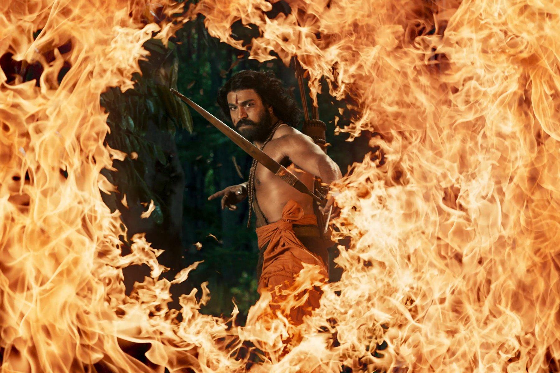 Kadr z filmu „RRR”, przedstawiający półnagiego mężczyznę z łukiem, którego postać otoczona jest ogniem.