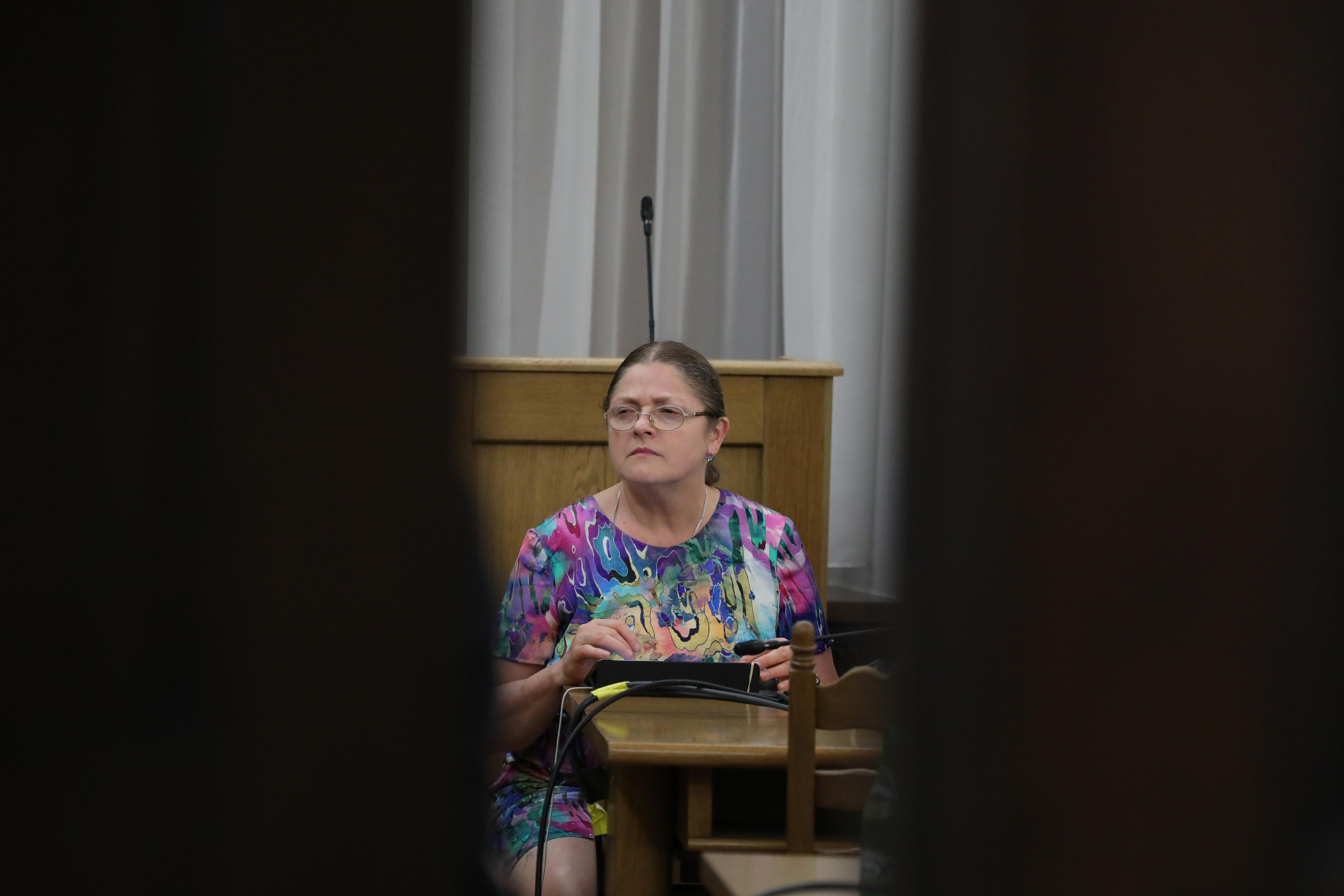 Krystyna Pawłowicz zamyślona siedzi za kotarą