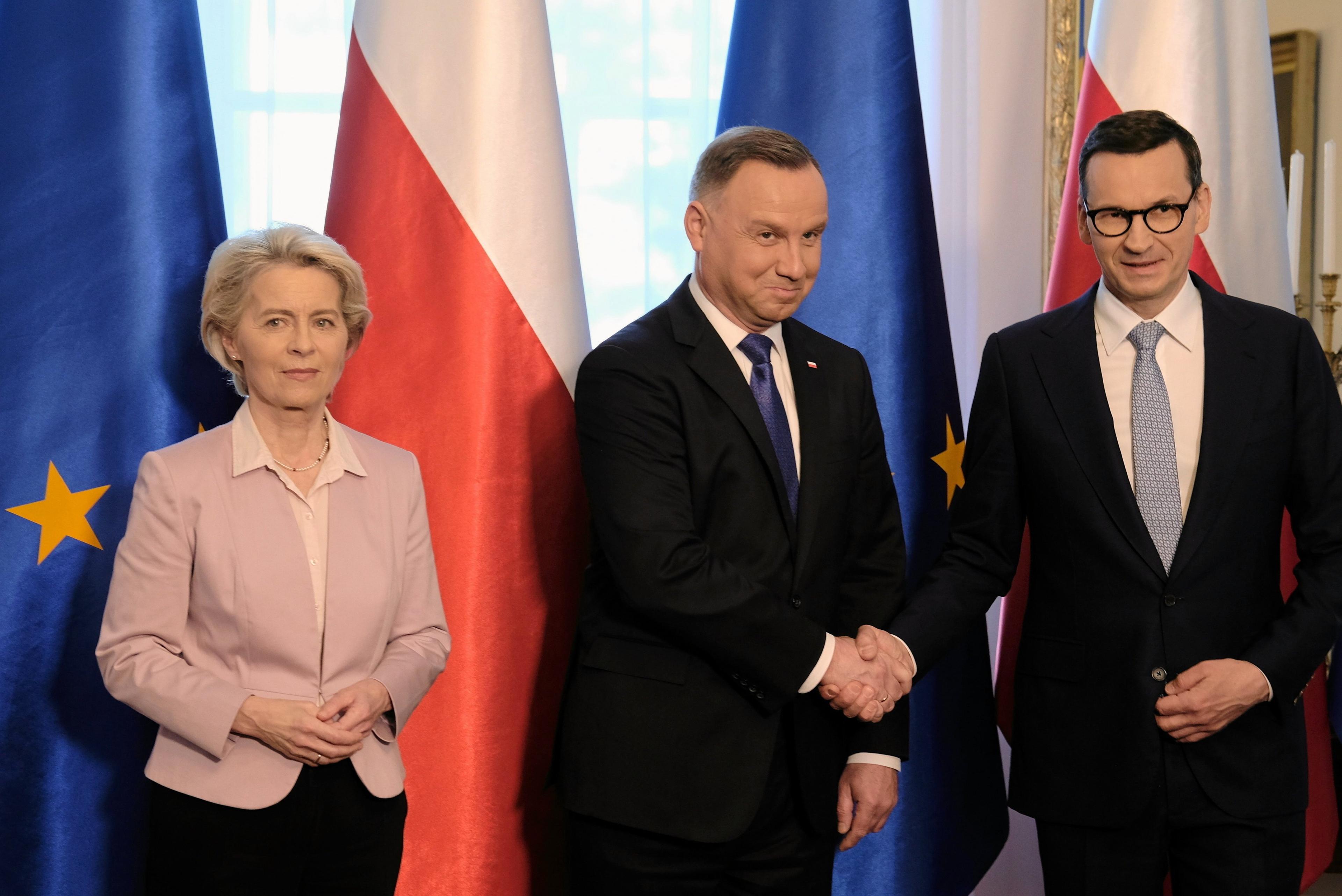 Ursula von der Leyen, Andrzej Duda i Mateusz Morawiecki na tle flag Polski i Unii