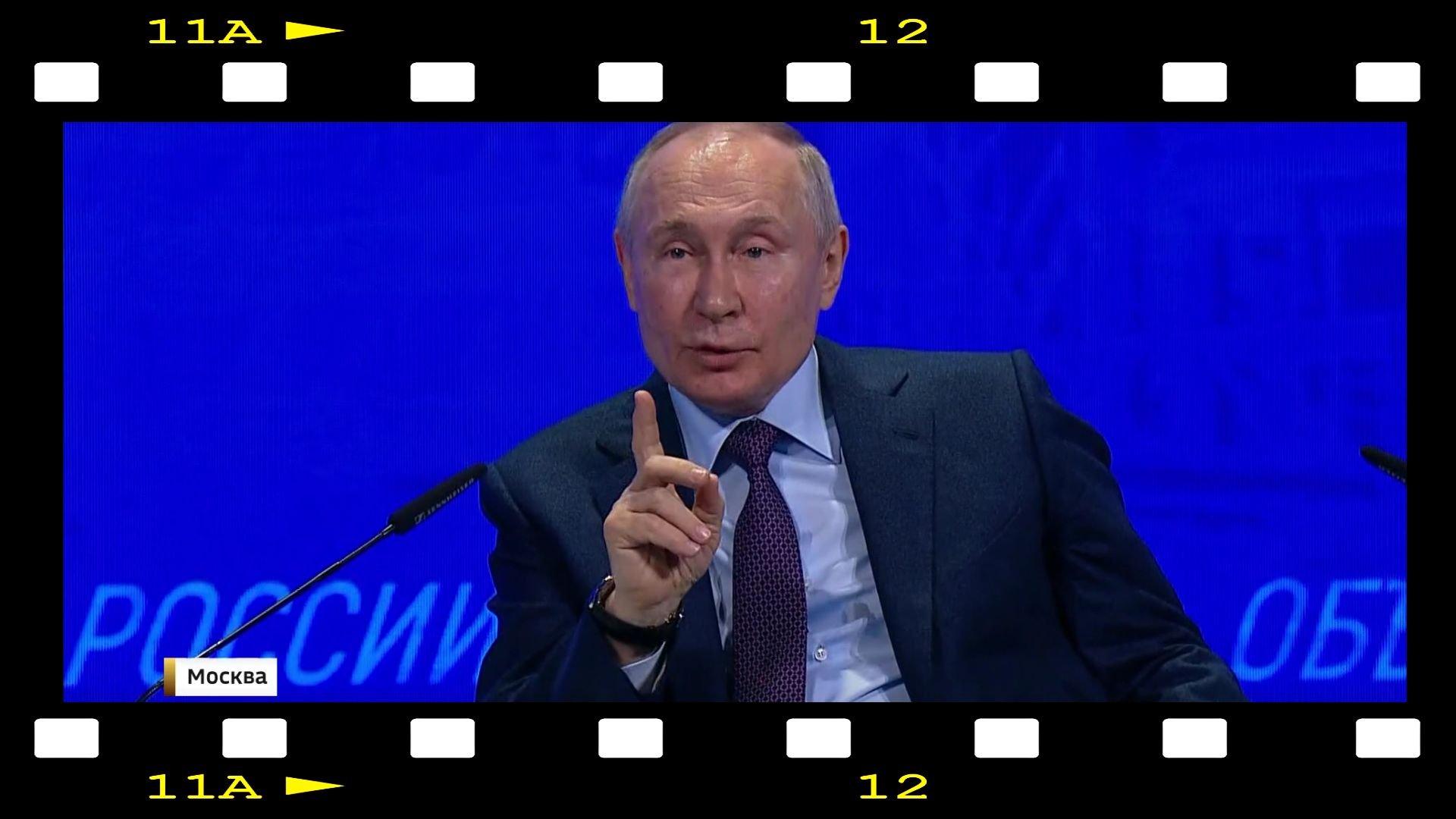 Kadr: zdjecie Putina w ramce filmowej. Putin ma uniesiony palec