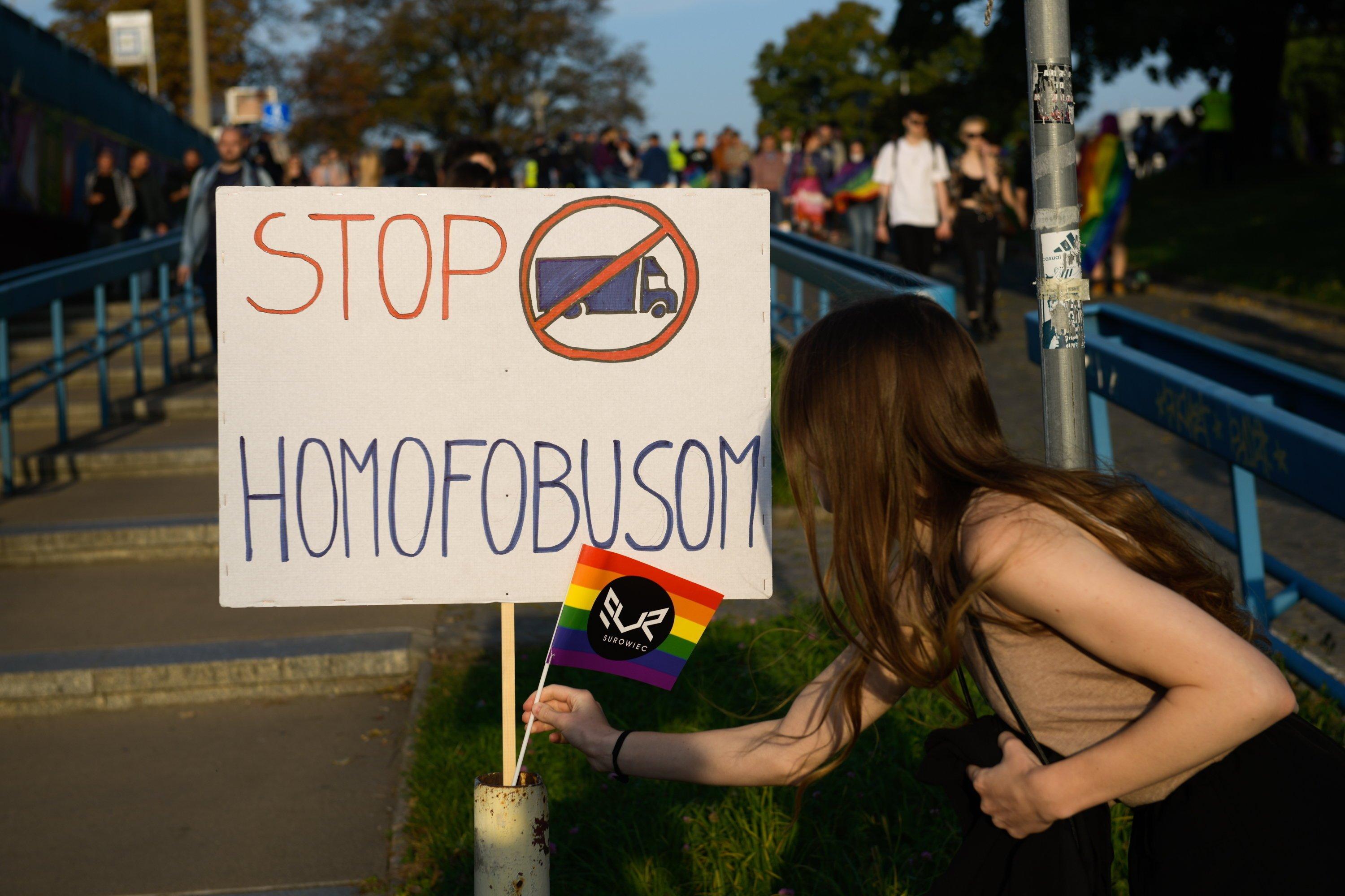 Na zdjęciu plakat "stop homofobusom" i tęczowa flaga
