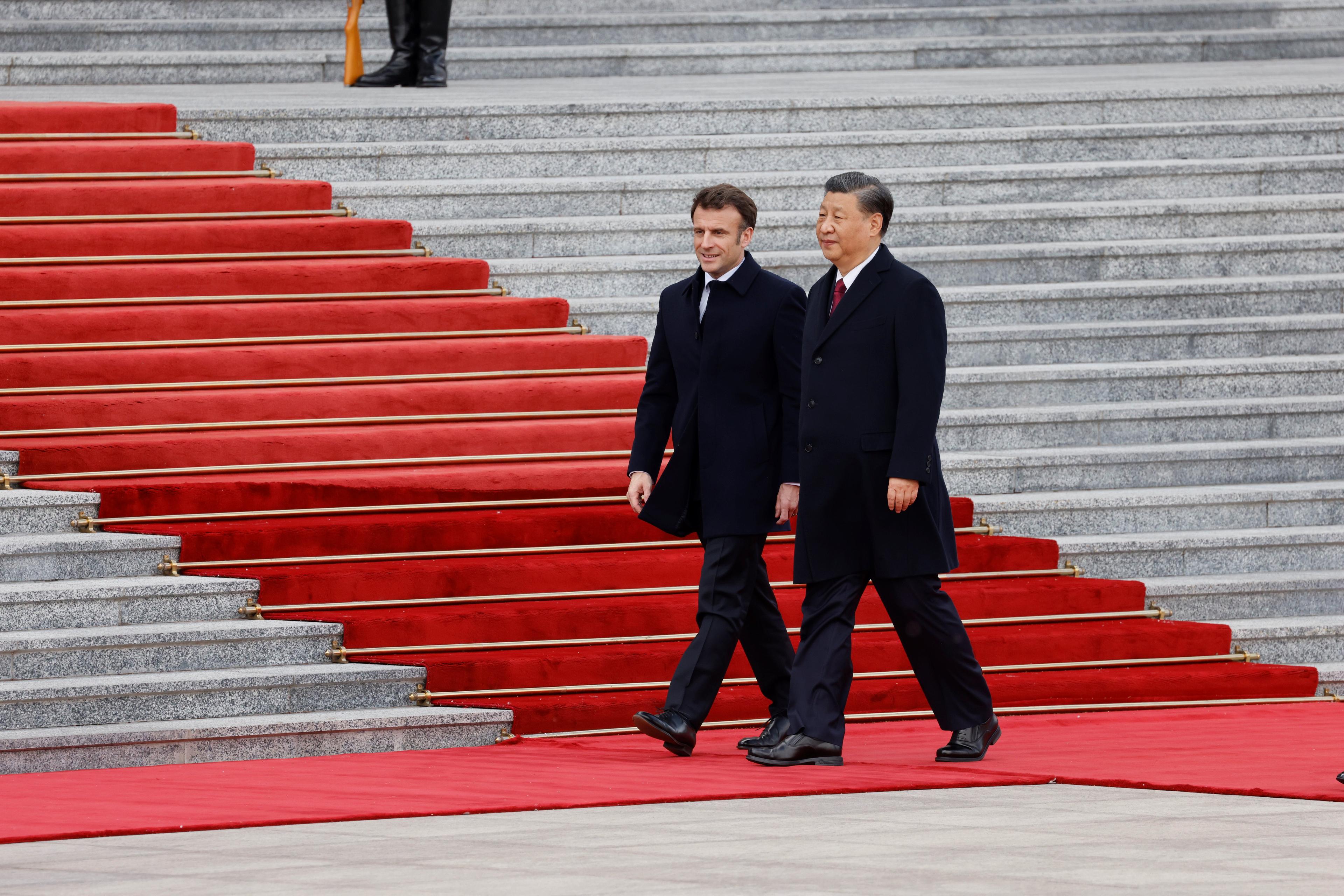 Dwaj mężczyźni w ciemnym ubraniu u stóp schodów z czerwonym dywanem