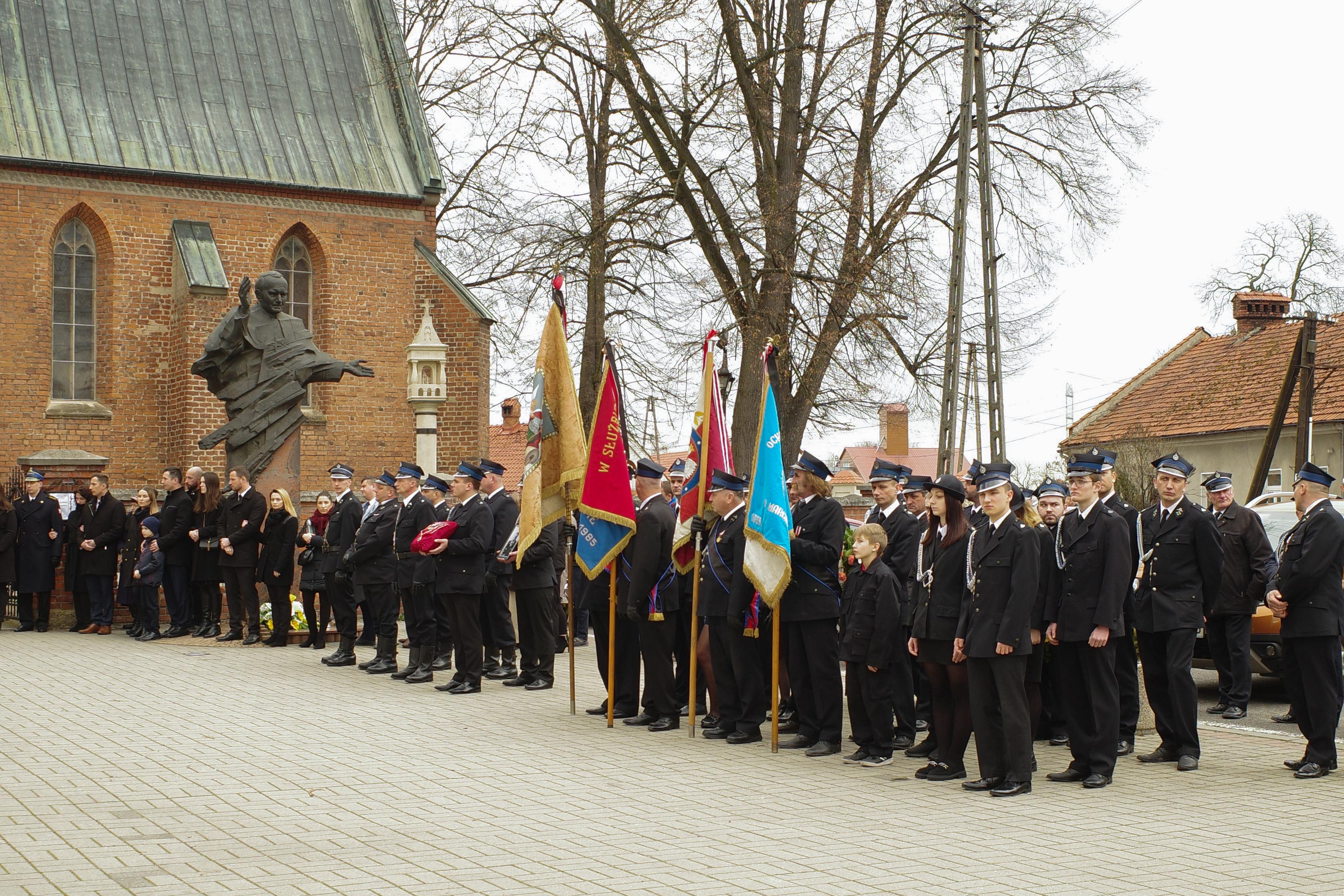 strażacy w galowych mundurach stoją pod kościołem, pogrzeb komendanta OSP w Radłowie