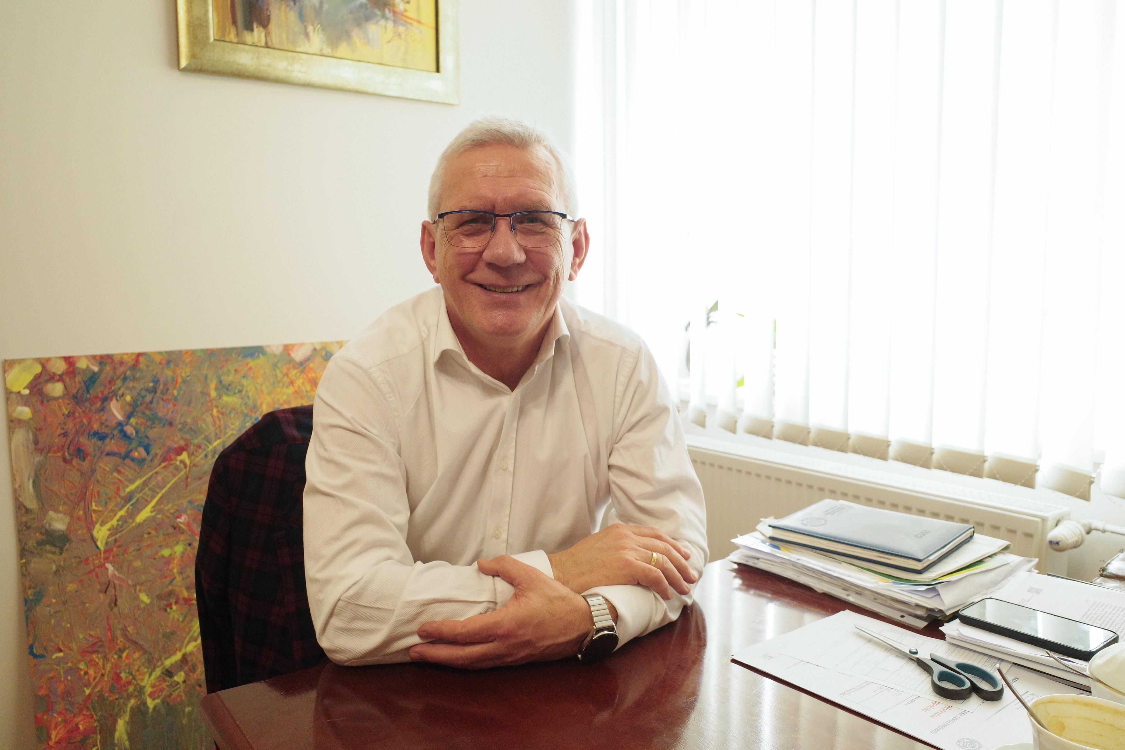 W białej koszuli, przy biurku uśmiechnięty Zbigniew Mączka, burmistrz Radłowa