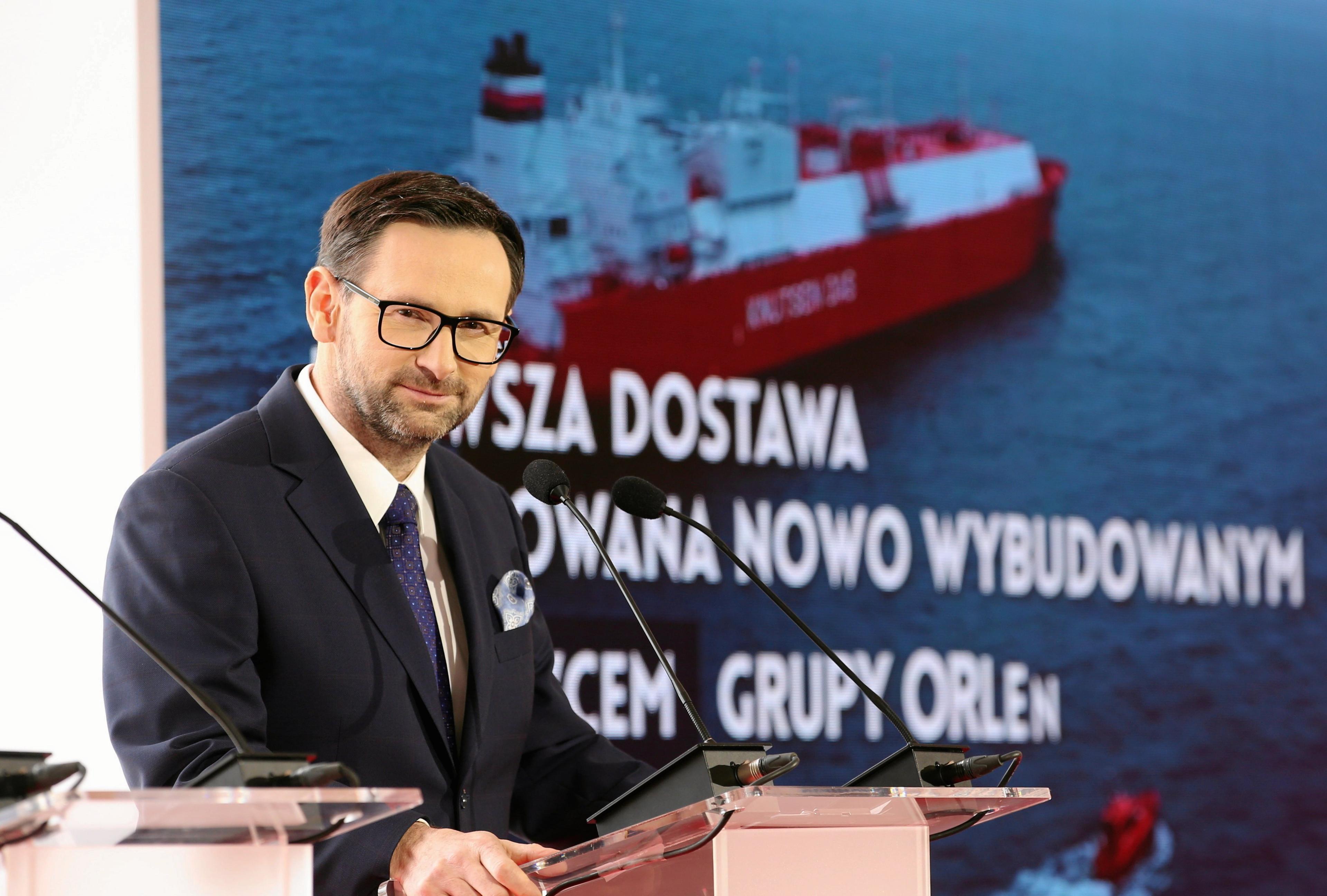 prezes Orlenu Daniel Obajtek podczas konferencji prasowej. W tle plansza z wyświetloną prezentacją statku-gazowca "Lech Kaczyński"