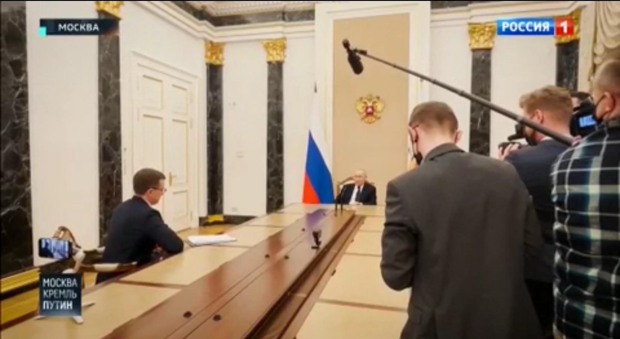 Putin siedzi u szczytu bardzo długiego stołu. Dźwiek zbiera mikrofon na długim wysięgniku