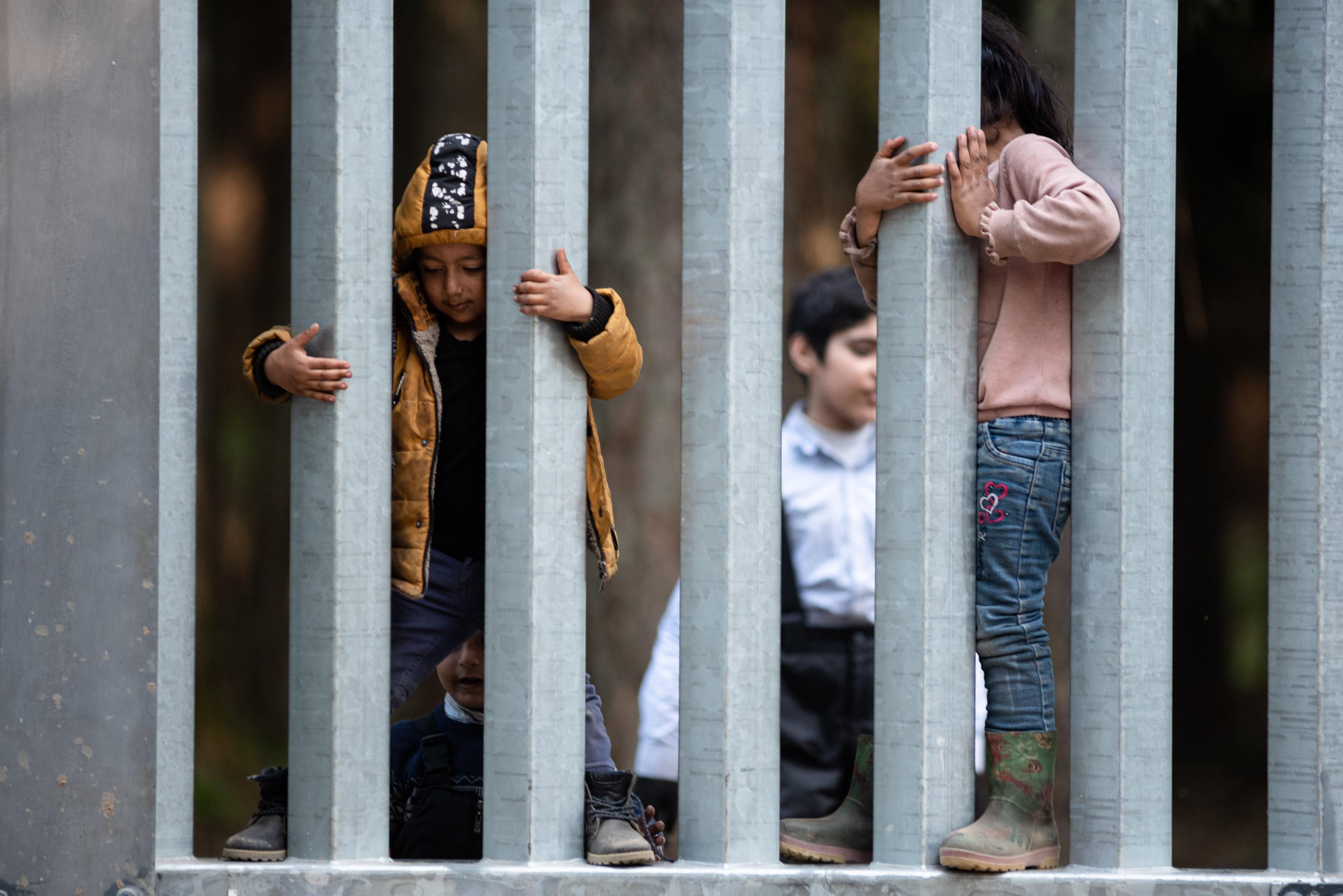 Dzieci wystawiające rączki przez zaporę na granicy