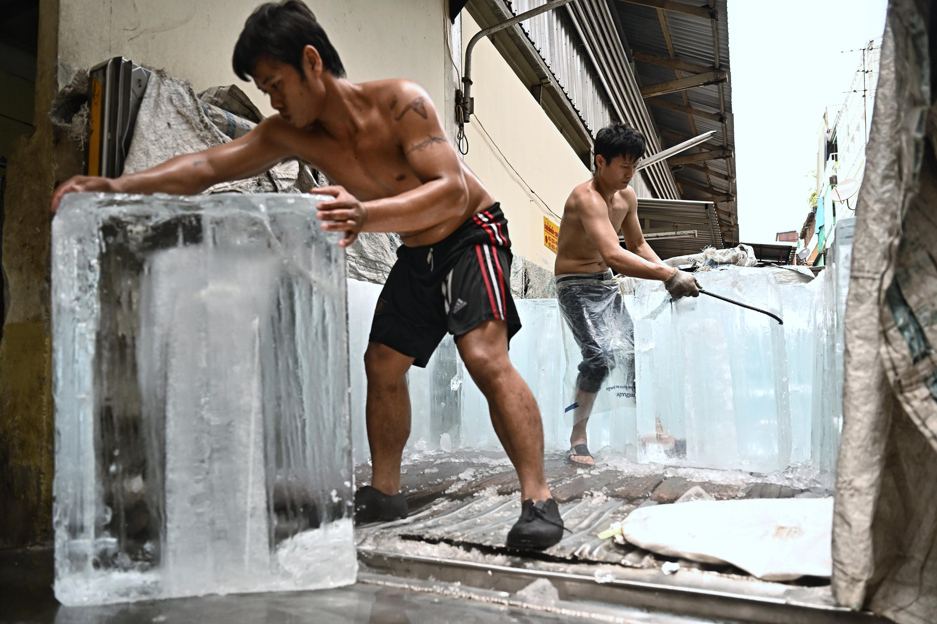 dwóch młodych robotników w bokserkach przesuwa wielkie bryły lodu