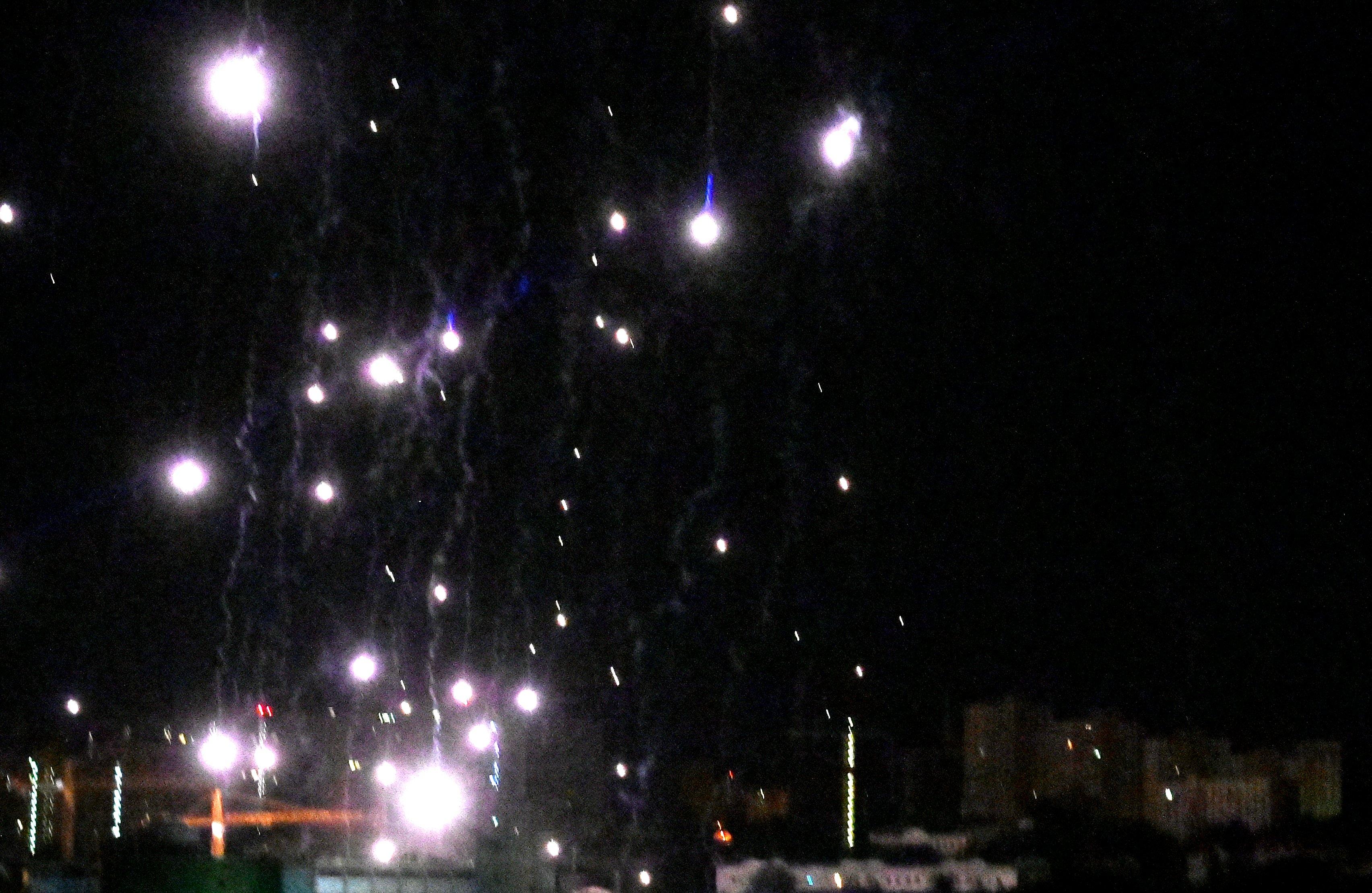 świecące na tle nocnego nieba spadające fragmenty drona
