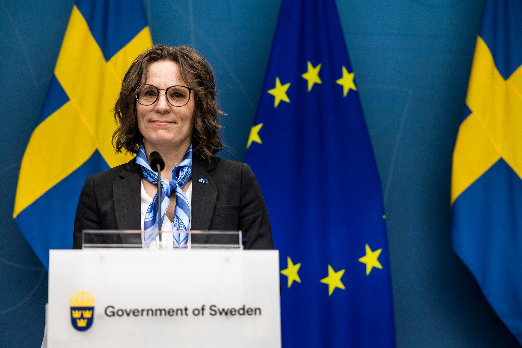 Szwedzka ministra spraw europejskich przemawia na tle flag UE i Szwecji