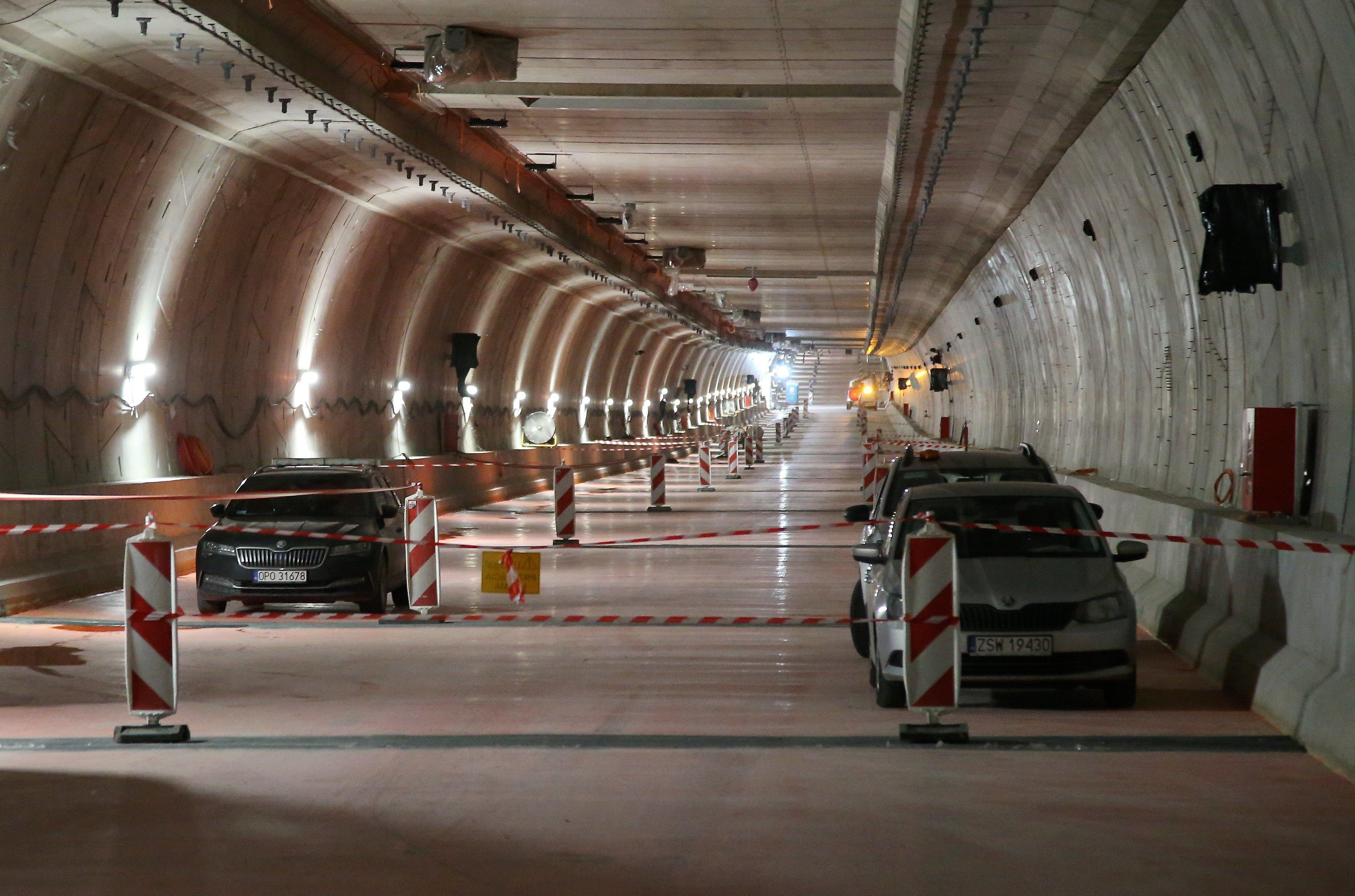 Budowa tunelu drogowego w Świnoujściu. Wnętrze tunelu ze słupkami zabezpieczającymi i samochodami wykonawcy