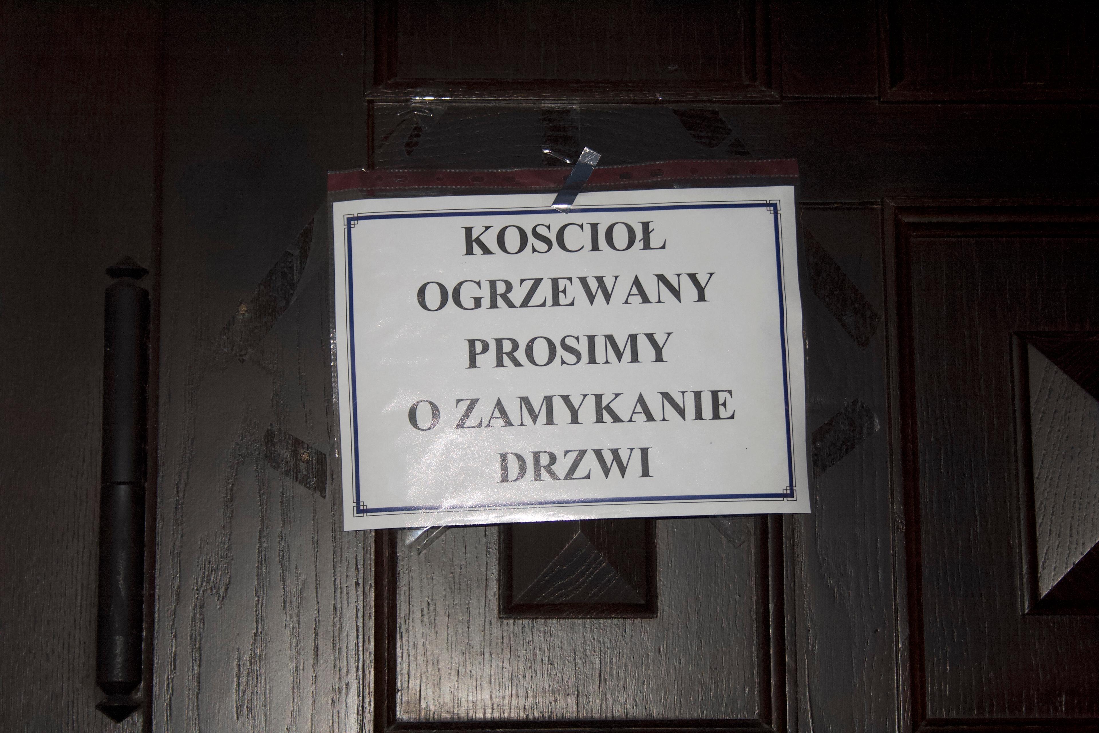 Przyklejona do drzwi kartka z napisem: "Kościół ogrzewany. Prosimy o zamykanie drzwi".