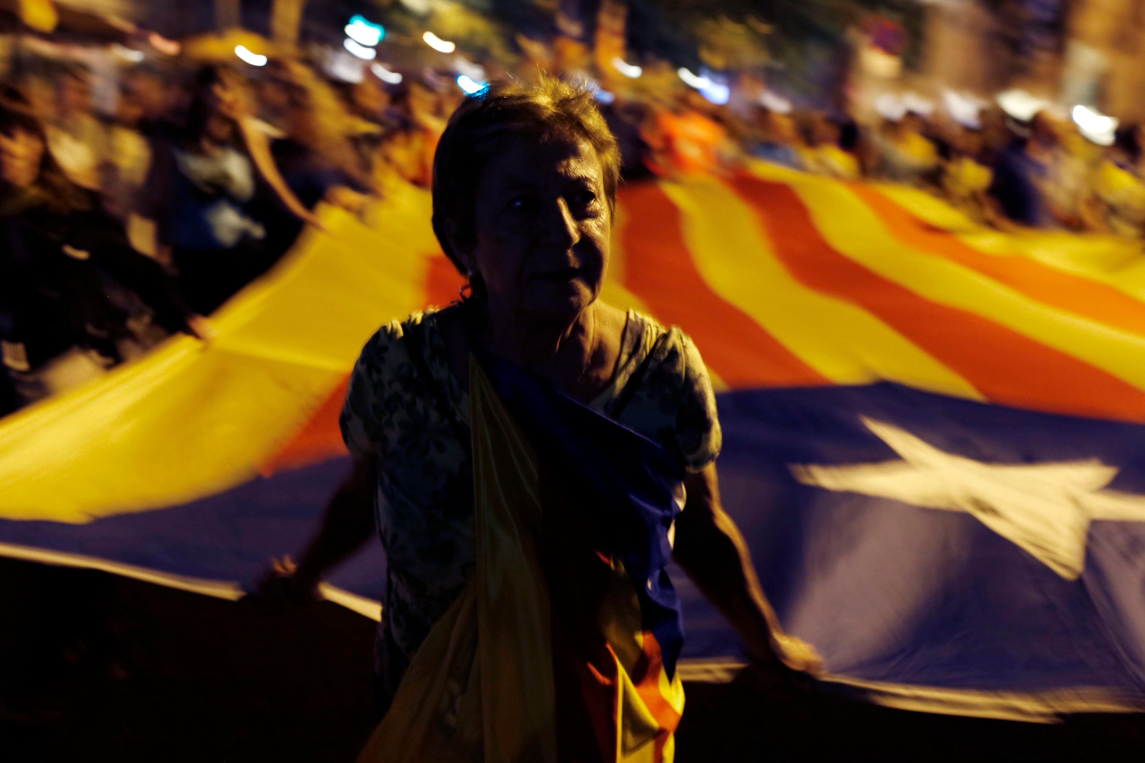Demonstrant stoi na tle wielkiej flagi Katalonii. Manifestacja w Barcelonie – Hiszpania.