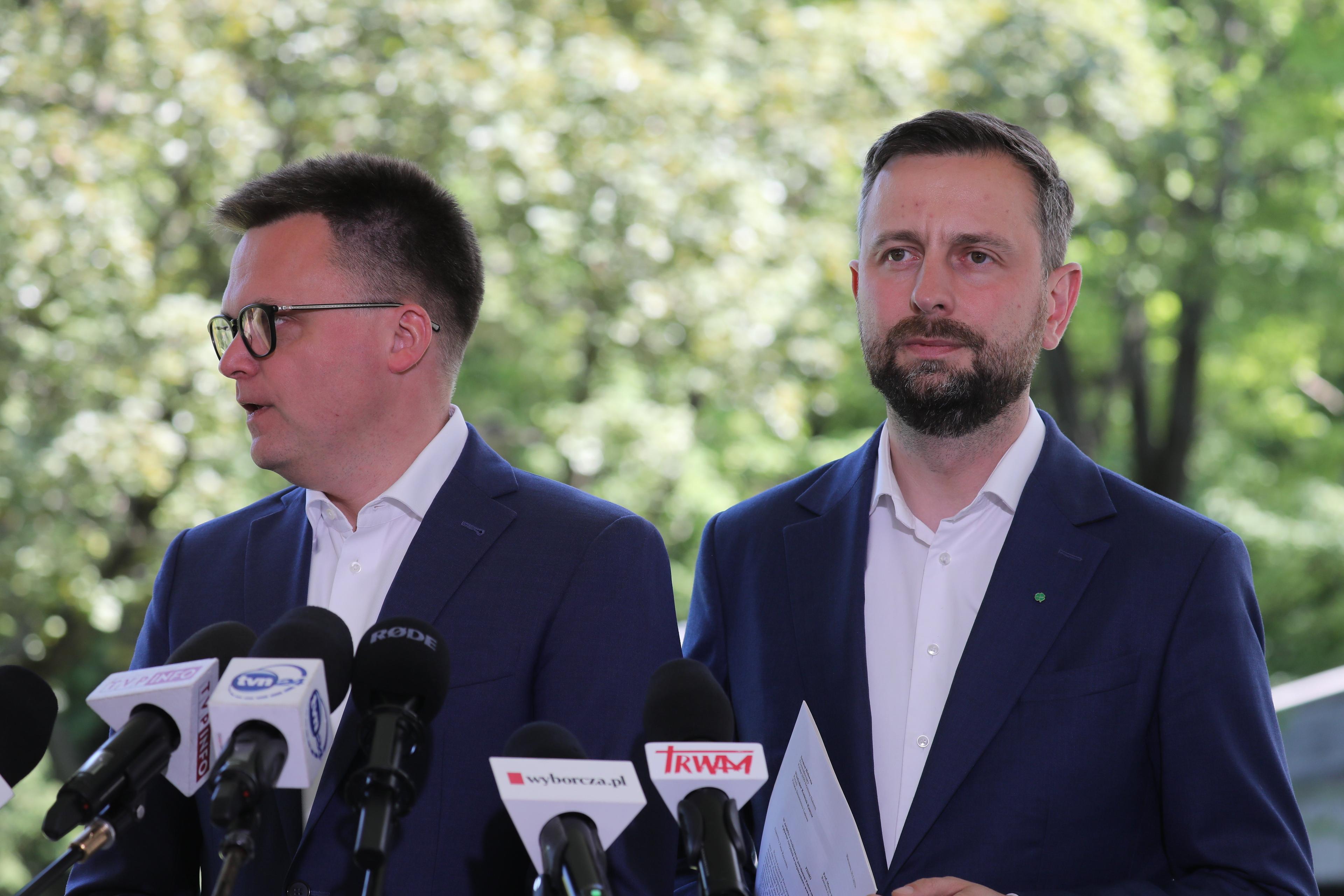 Szymon Hołownia i Władysław Kosiniak-Kamysz stoją przed mikrofonami mediów na tle drzew