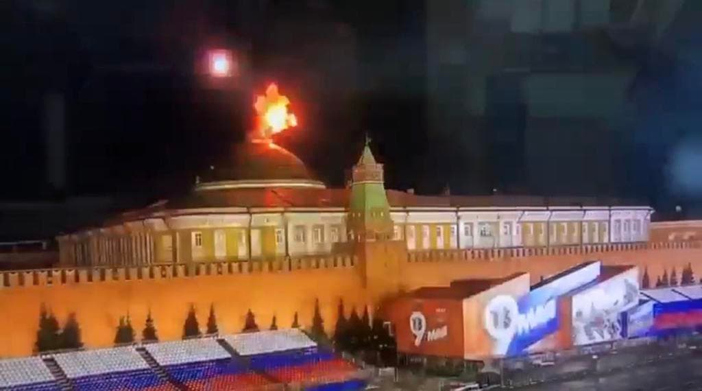 Eksplozja drona nad Kremlem, widać błysk ognia nad budynkami Kremla, poniżej trybuny i dekoracja, przygotowane na obchody Dnia Zwycięstwa