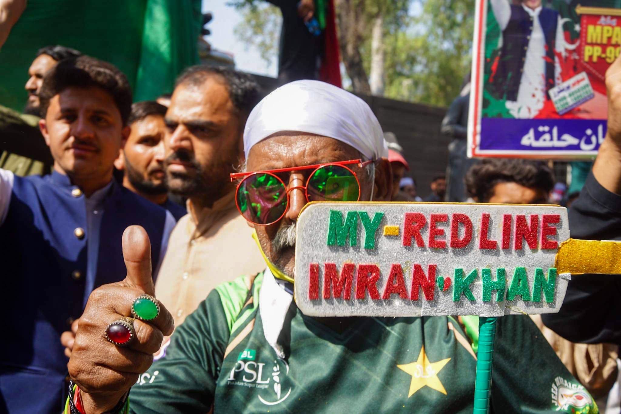 Demonstrant w kolorowych okularach trzyma plakat z napisem „My redline Imran Khan” (Moja czerwona linia Imran Khan)
