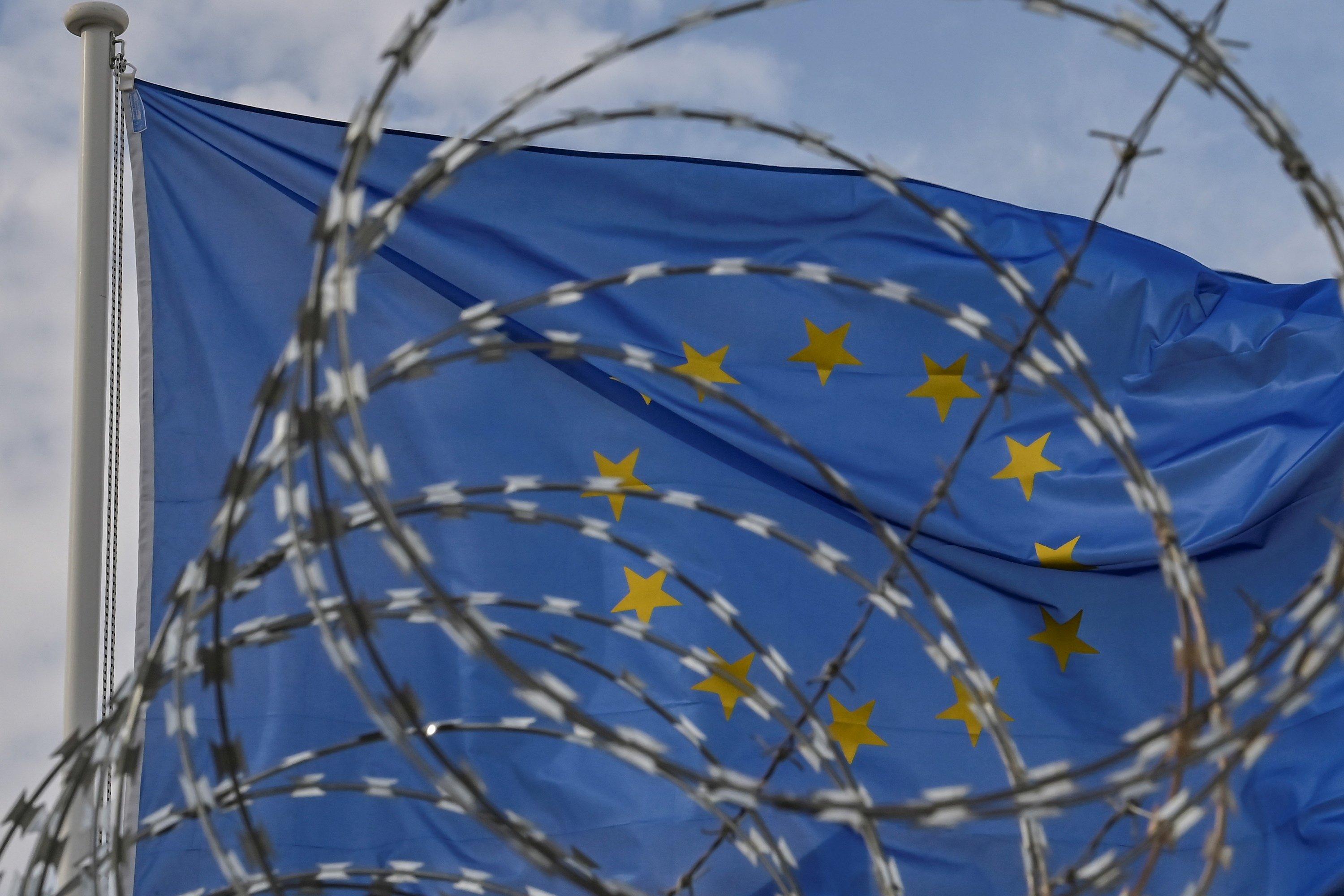 Flaga Unii Europejskiej powiewa za drutami kolczastymi