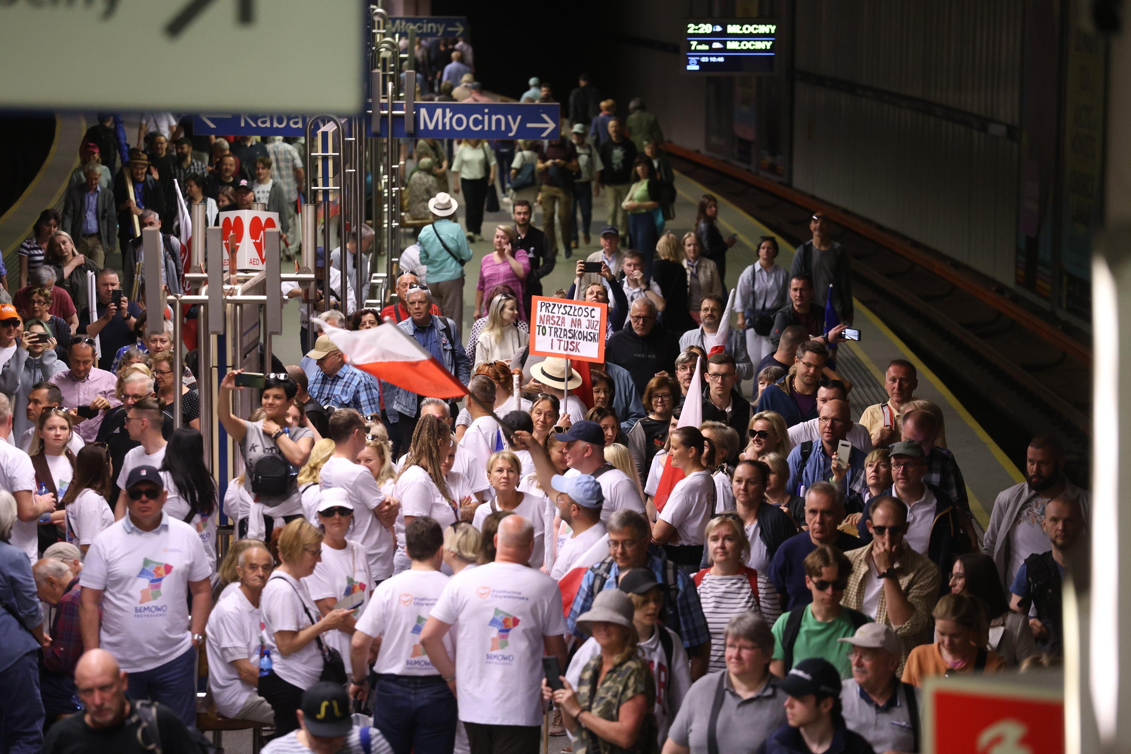 Tłum ludzi na peronie Dworca Centralnego, widać biało-czerwone flagi i transparenty