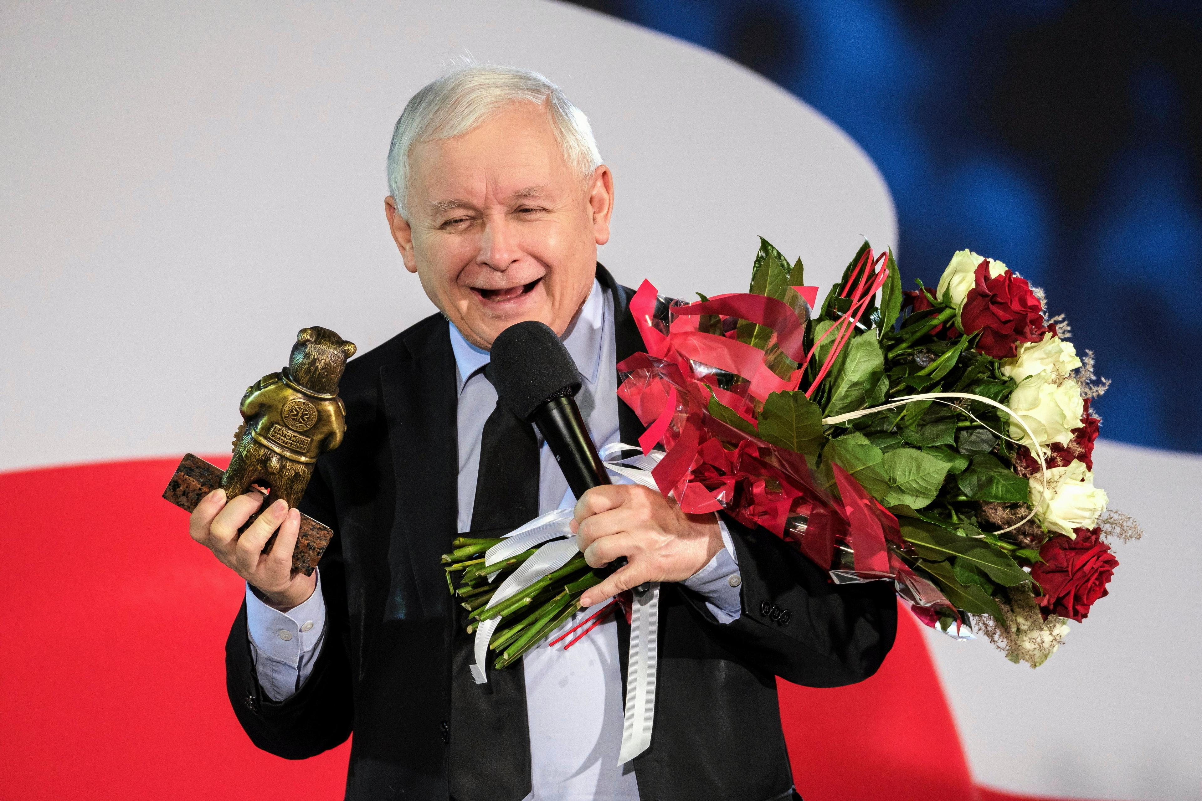 Uśmiechnięty Kaczyński odbiera bukiet kwiatów i statuetkę