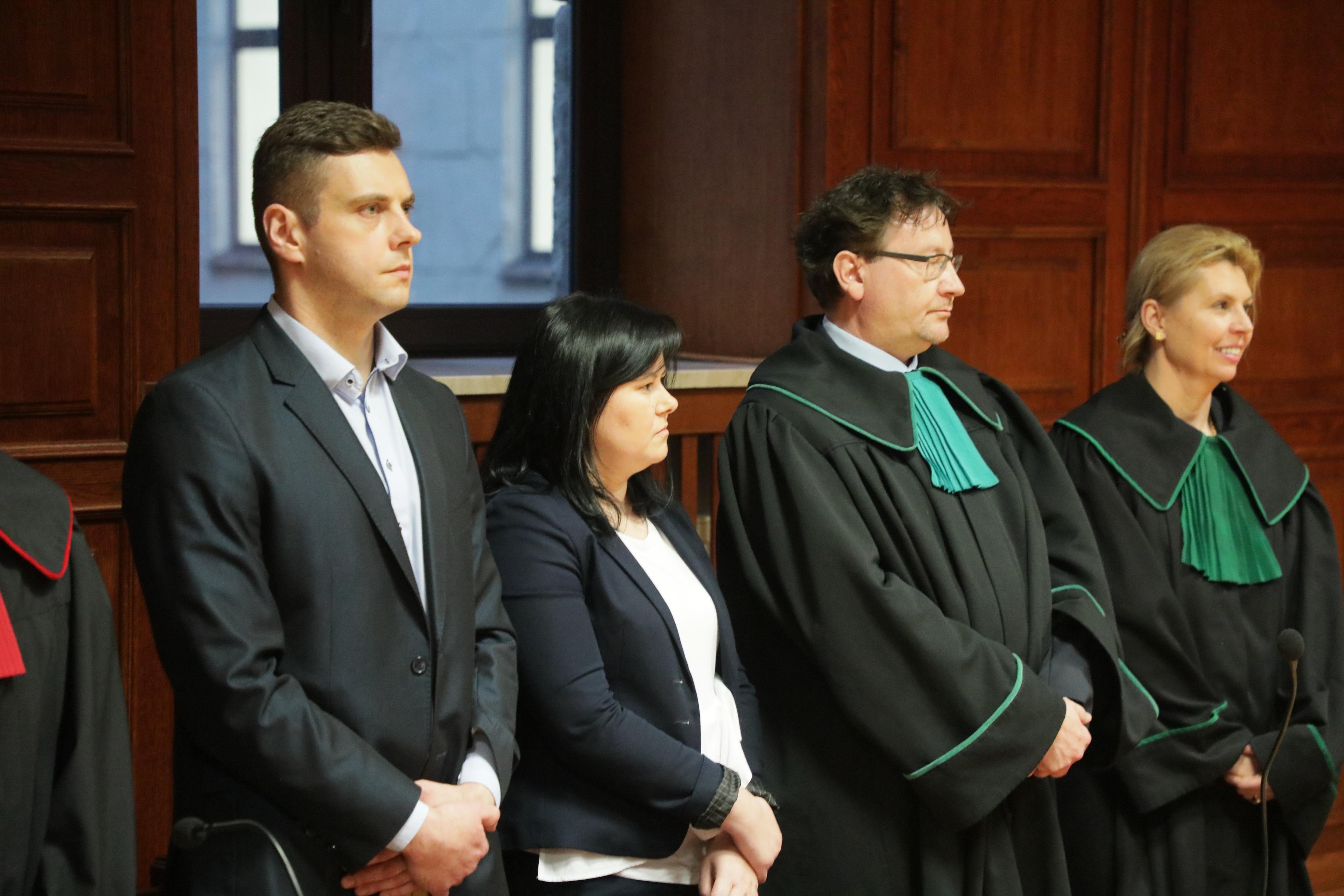 Dwoje ludzi (Kamil i Justyna Dziibakowie) stoją w sądzie obok swoich adwokatów