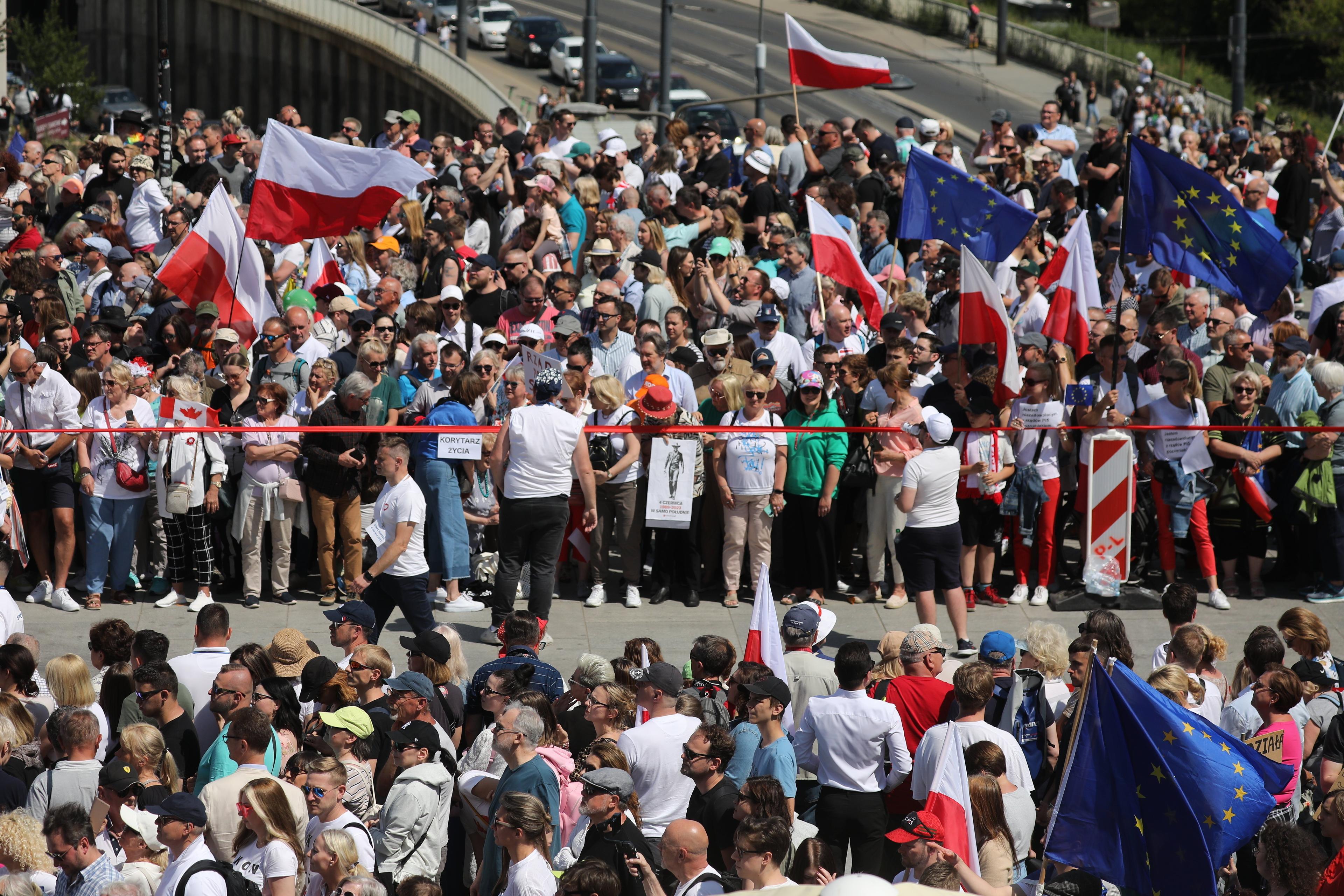 Tłum na ulicy, ludzie trzymają flagi Polski i UE