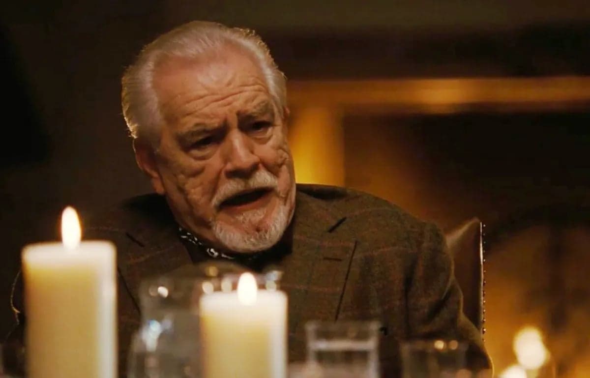 Kadr z serialu „sukcesja”. Starszy mężczyzna z brodą (Logan Roy) siedzi za stołem, na którym palą się świece.