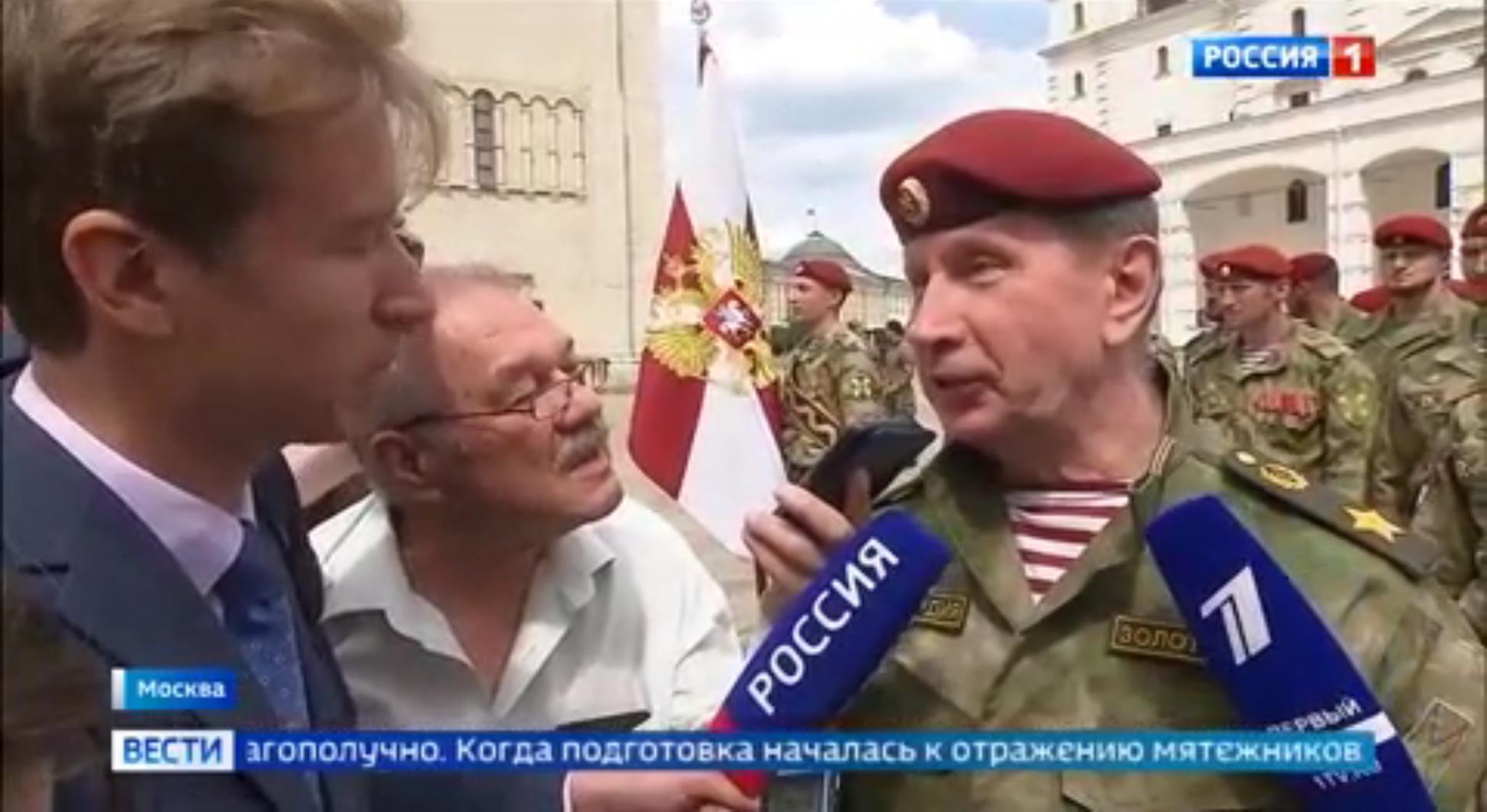 Męzczyzna w mundurze polowym i bordowym berecie mówi do mikrofonu pracownika pierwszego kanału rosyjskiej TV